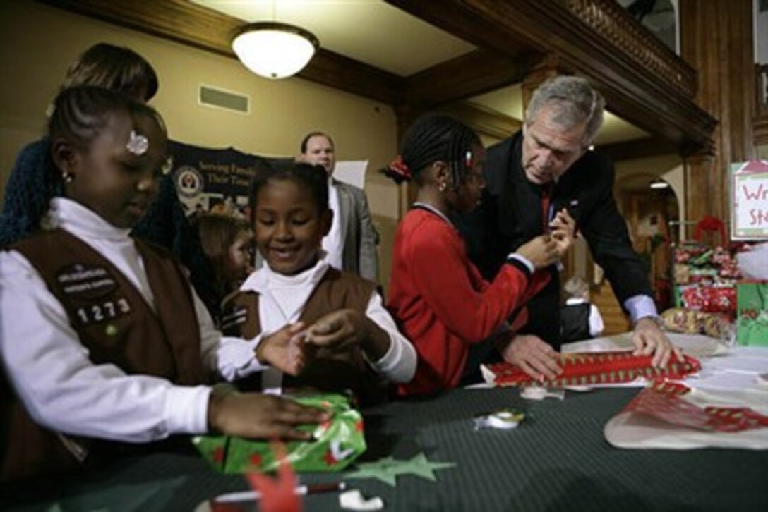 President George W. Bush helps young volunteers wrap presents for families of soldiers who were wounded in Iraq and Afghanistan, Dec. 22, 2006, at Walter Reed Army Medical Center, in Washington, D.C.
