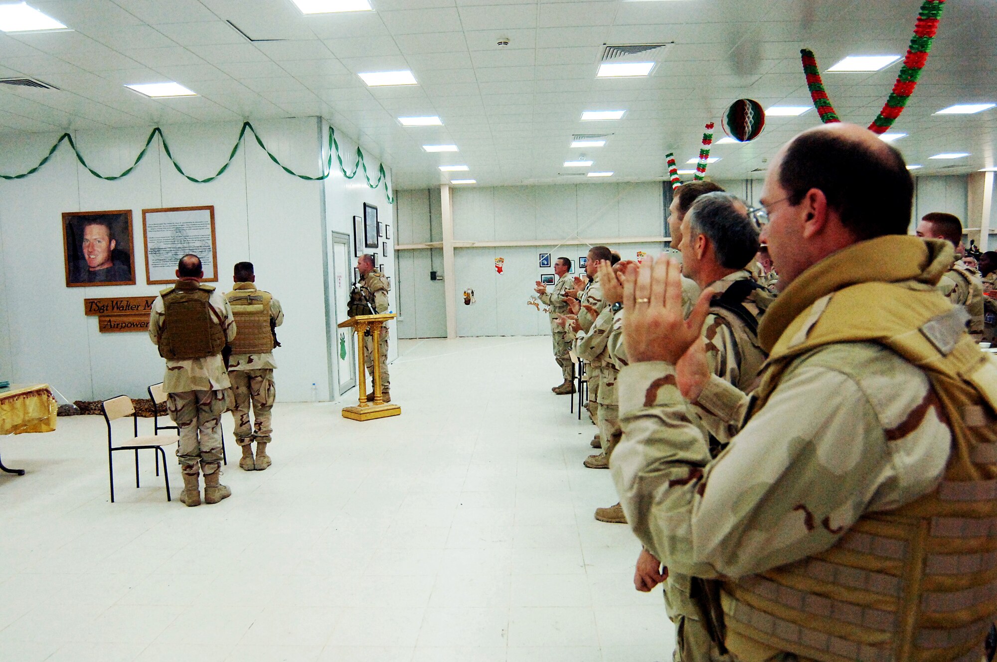 Members of the 447th Air Expeditionary Group at Sather Air Base in Baghdad applaud during a ceremony Dec. 25 marking the opening of the Tech. Sgt. Walter M. Moss Airpower dining facility. Sergeant Moss, an explosive ordnance disposal team leader, was deployed to Sather Air Base when he was killed in action in March. (U.S. Air Force photo/Staff Sgt. Scott McNabb)