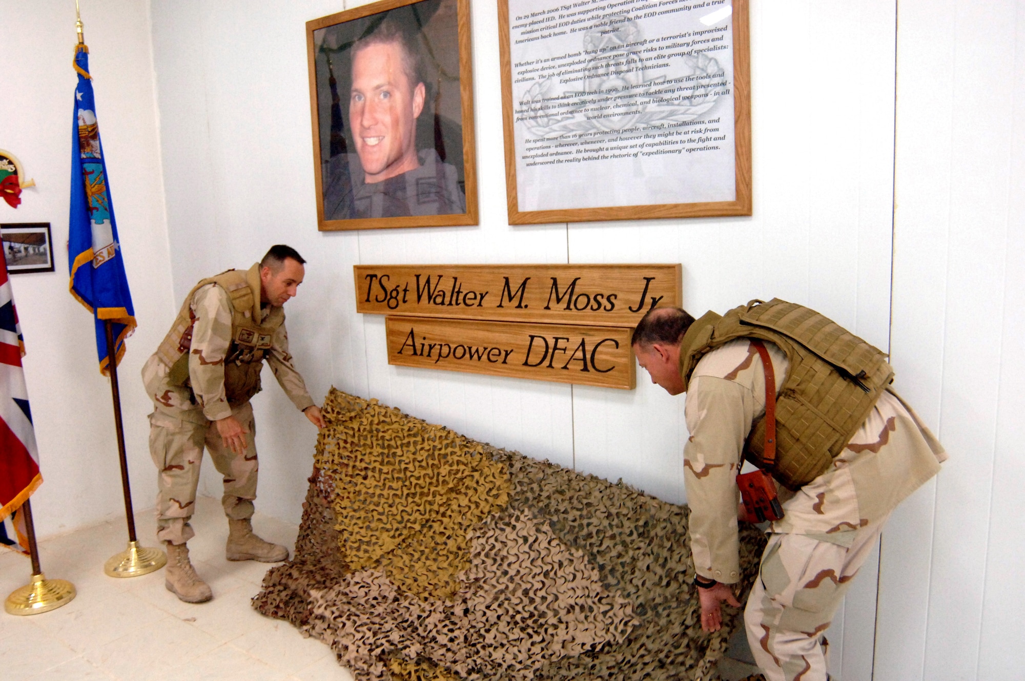 Col. Gregory Marston (left) and Lt. Gen. Gary North take down camouflage netting to reveal the carved sign and memorial to Tech. Sgt. Walter Moss, an explosive ordnance disposal team leader who was deployed to Sather Air Base in Baghdad when he was killed in action in March.  The unveiling was part of an opening ceremony Dec. 25 for the new dining facility at Sather named in honor of Sergeant Moss.  General North is the U.S. Central Command Air Forces commander and Colonel Marston is the 447th Air Expeditionary Wing commander.  (U.S. Air Force photo/Staff Sgt. Scott McNabb)