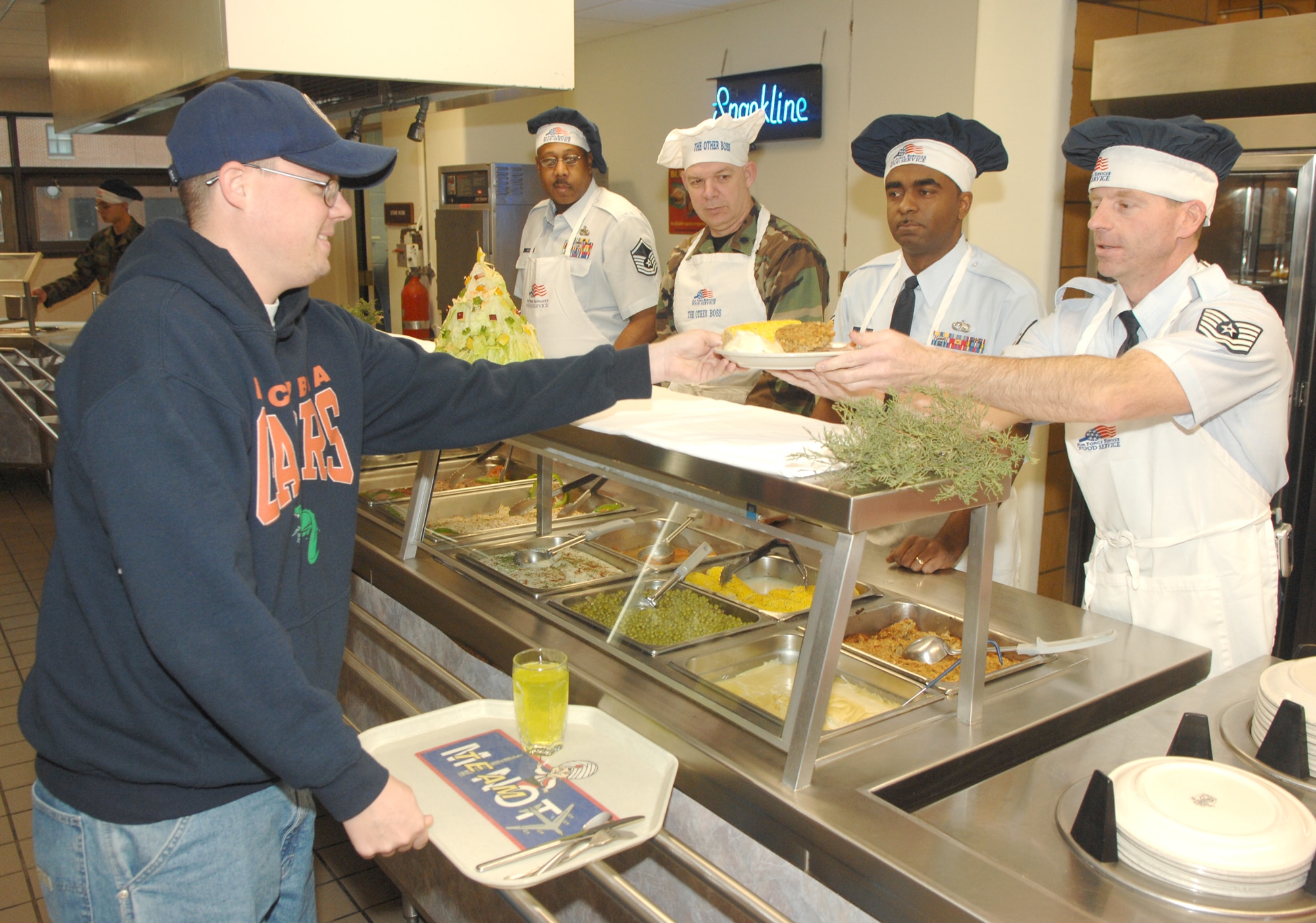 Senior Airman Daniel Vining, 5th Maintenance Squadron, recieves a plate of food from Tech. Sgt. Michael Juda, 5th Communications Squadron, at the Dakota Inn Dining Facility Christmas Day. On holidays suchs as Christmas and Thanksgiving, the dining facility is staffed by members of Minot Air Force Base leadership and other volunteers, who serve lunch and dinner to dormitory residents. (U.S. Air Force photo by Airman 1st Class Christopher Boitz) 
