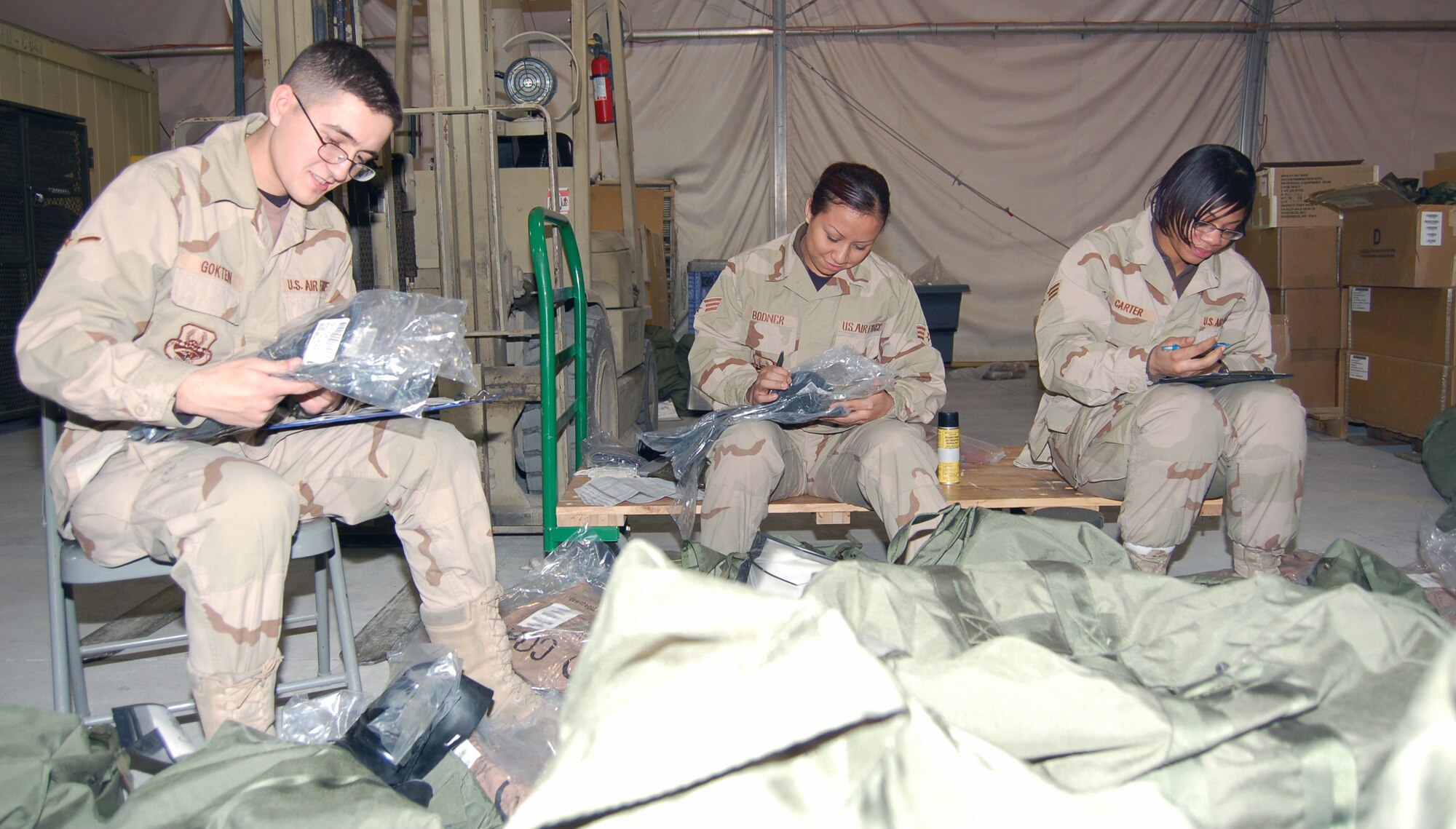 Airman Alper Gotken, Senior Airman Brenda Bodner and Senior Airman Ebony Carter, 376th Expeditionary Theater Distribution Center technicians, sift through bags of equipment that were turned in to the ETDC. Their job is to ensure serviceability and shelf life of all assets turned in and replaces any items for reissue to Airmen headed for Afghanistan. All three are deployed from the 319th Logistics Readiness Squadron at Grand Forks Air Force Base, N.D. (U.S. Air Force photo/Master Sgt. Mitch Gettle)