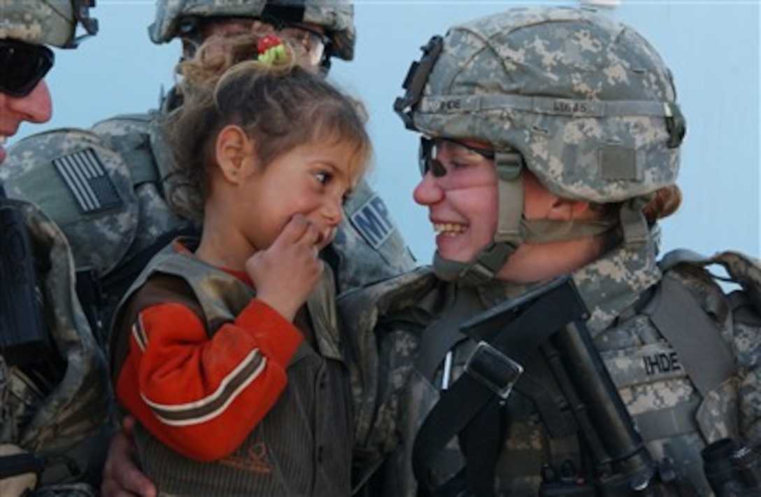 U.S. Army Sgt. Krista Ihde talks to an Iraqi girl during a visit to the provincial Iraqi police headquarters in Diwaniyah, Iraq, on Dec. 20, 2006.  Ihde is a team leader with 3rd Platoon, 984th Military Police Company, Police Transition Team, Camp Echo, Iraq.  