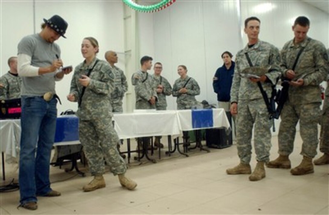 Musician Kid Rock autographs a compact disc for U.S. Army Spc. Chelsea Stepp, a paratrooper with the 4th Brigade Combat Team (Airborne), 25th Infantry Division, as other soldiers wait in line during Rock's visit to Forward Operating Base Kalsu, Iraq, Dec.24, 2006.