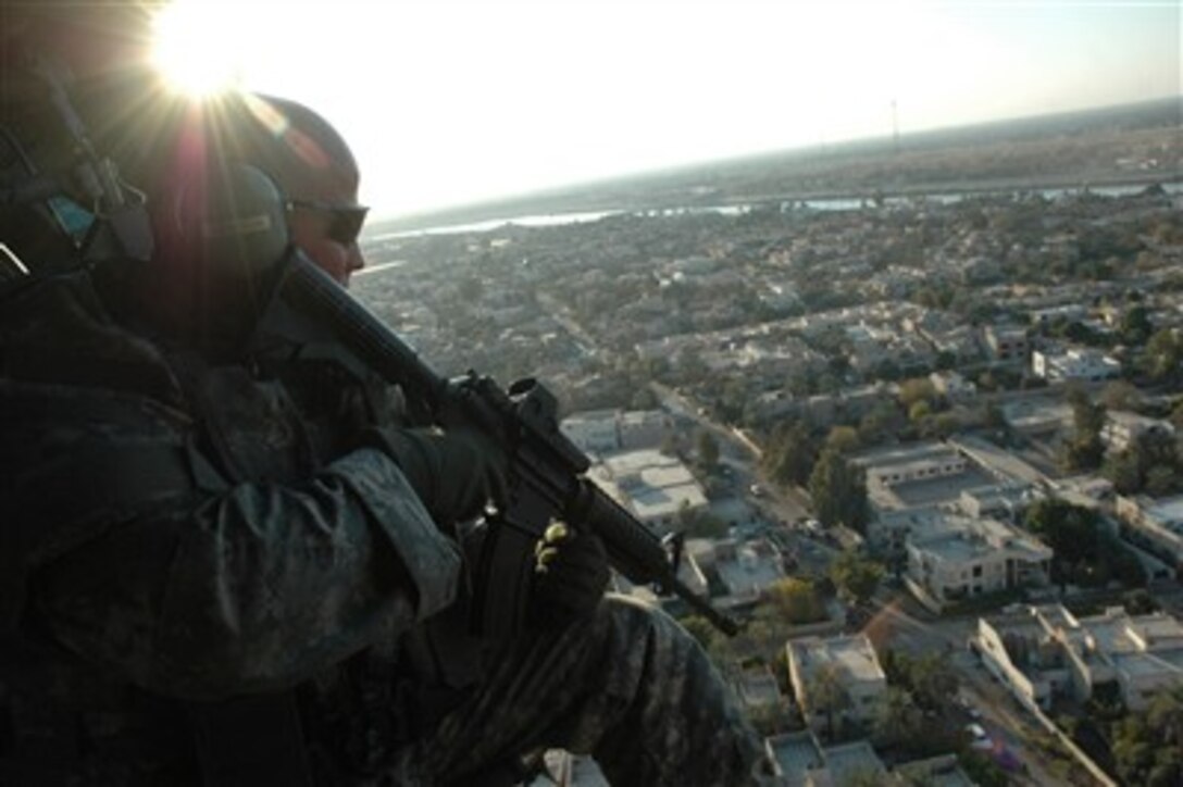 U.S. Army Spc. Jed Alfalla looks out over Baghdad, Iraq, from aboard a UH-60 Black Hawk helicopter, Dec. 24, 2006. Alfalla serves on the protective service detail of Lt. Gen. Ray Odierno, the commander of Multi-National Corps - Iraq, providing protection during Odierno's travels.