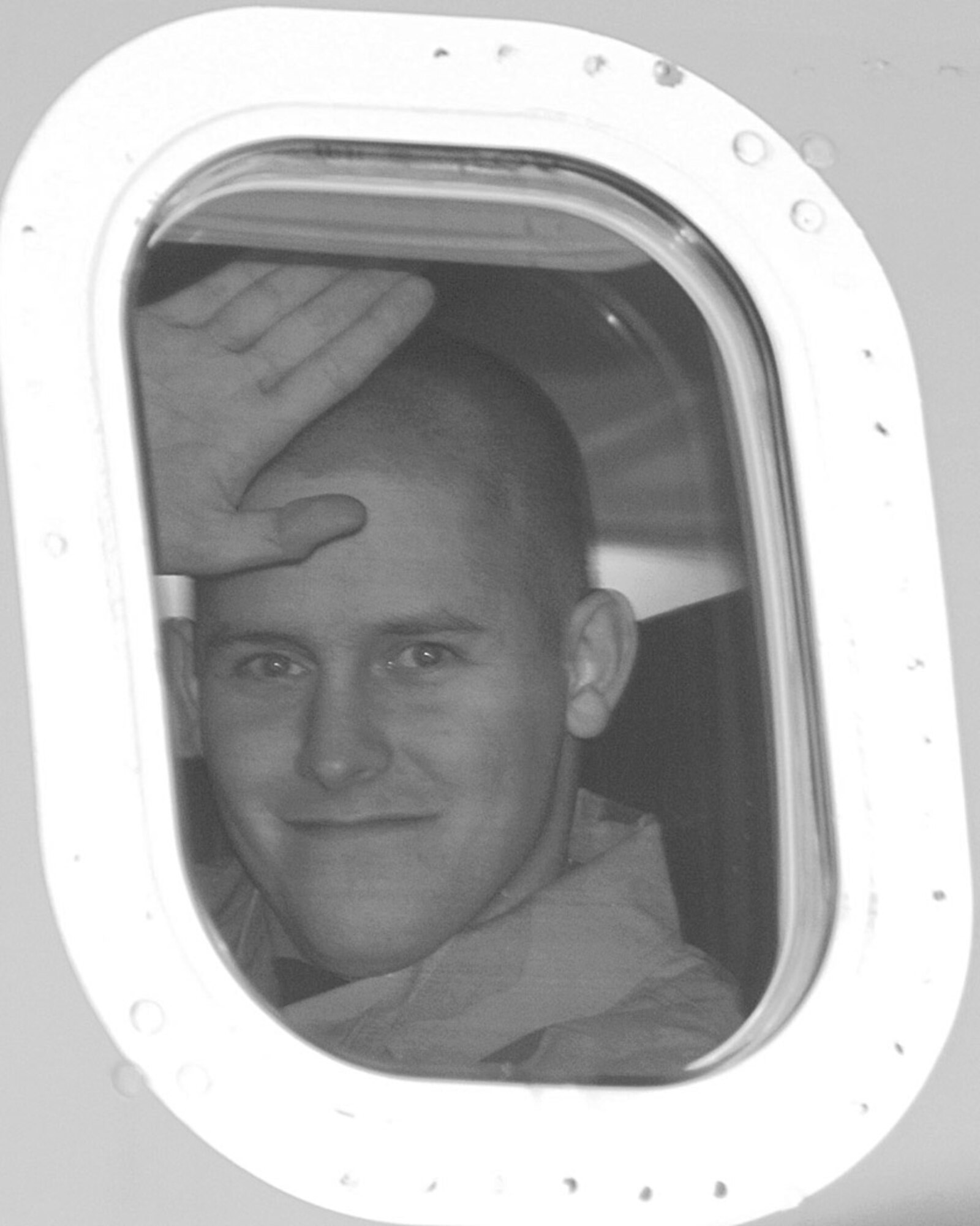 Senior Airman Matthew Fritz, 49th Communications Squadron, waves goodbye to Holloman from his aircraft window as he deploys overseas Monday.