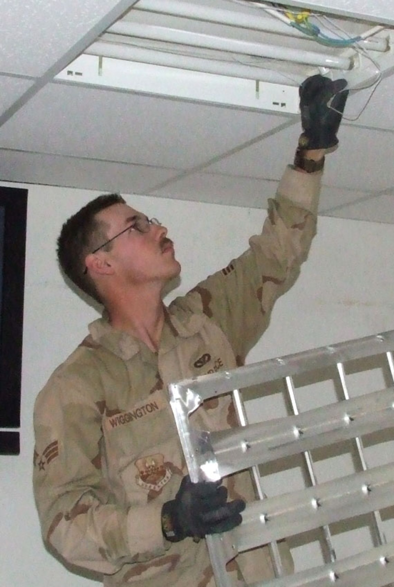 Senior Airman Ray Wiggington installs light fixtures in a building being renovated at Contingency Operating Base Speicher, Iraq.  Airman Wiggington, assigned to Detachment 10 of the 732nd Expeditionary Civil Engineer Squadron, is deployed to Speicher from Ellsworth Air Force Base, S.D.  (U. S. Air Force photo/Maj. Richard Sater)