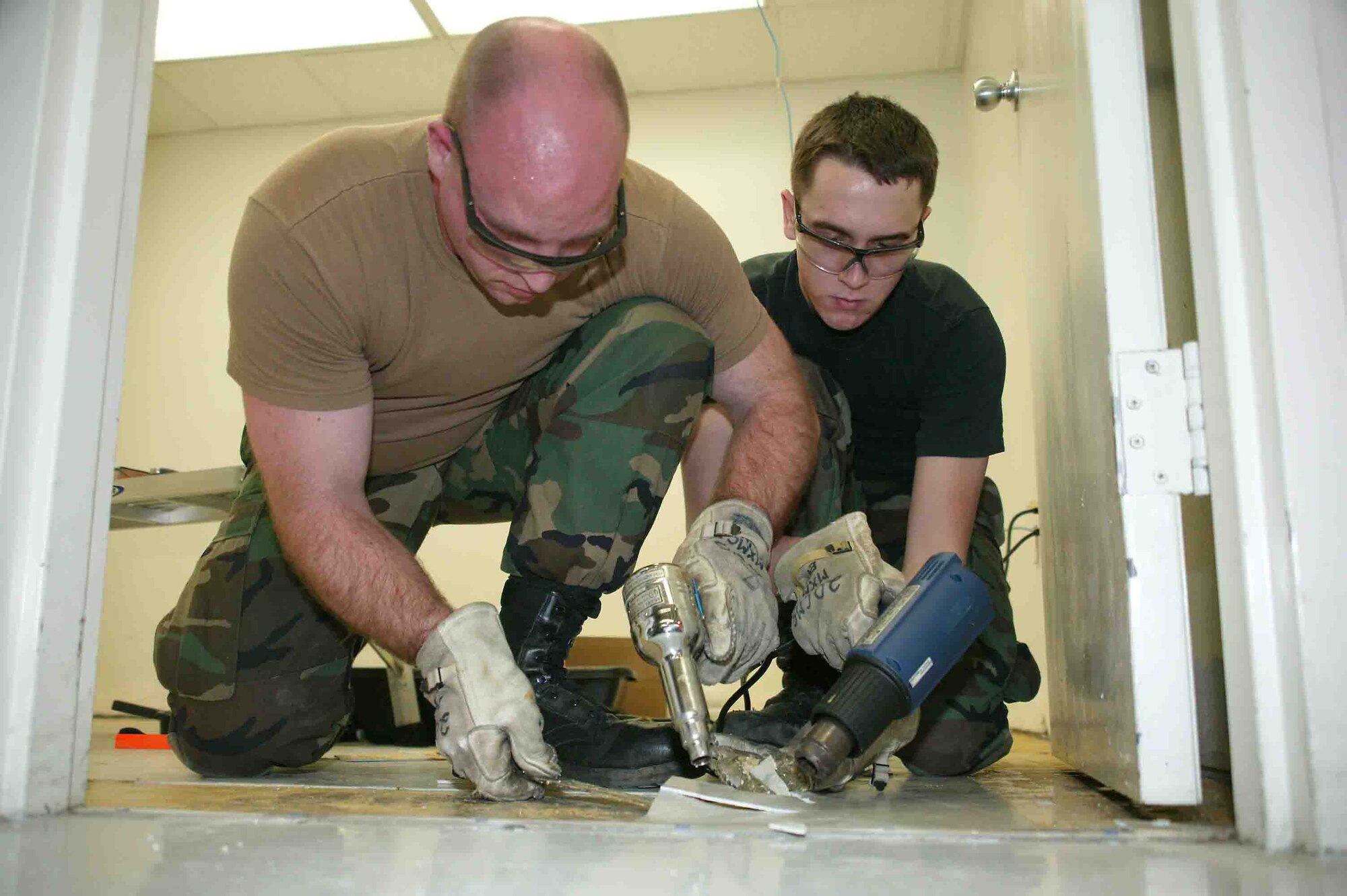 SHAW AIR FORCE BASE, S.C.-- Staff Sgt. Nathan Weigel (left) and Airman 1st Class Carl Disher, 20th Component Maintenance Squadron Electrical Environmental technicians, remove damaged tile from the oxygen room Dec. 27. The room is used to store bottles of oxygen, which are mounted on the ejection seats of the F-16 Fighting Falcon. The room was damaged during a fire in May. (U.S. Air Force photo/Senior Airman John Gordinier)