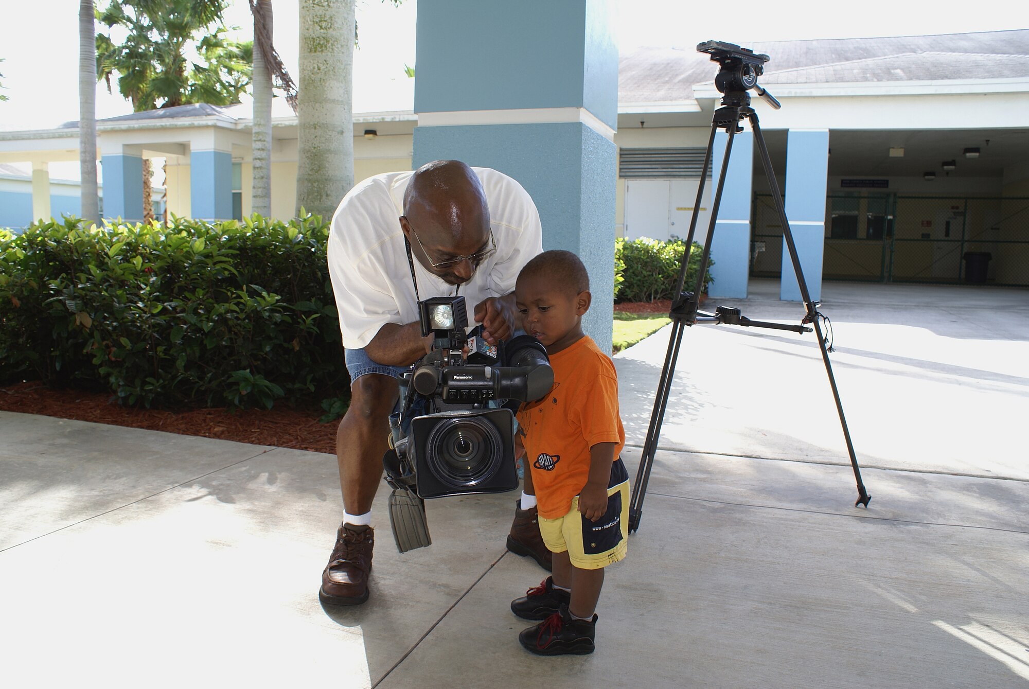 Nineteen-month old Jaheim Bynum inspects the camera of CBS-4 journalist Waverly Allen while waiting for the arrival of Santa.  Dozens of children at Community Partnership for Homeless in Homestead, Fla. got to meet Santa and his “elves: from the 482nd Medical Squadron on Dec. 3.  The event was part of a community outreach program sponsored by the Homestead Air Reserve Base Junior Enlisted Council.  (Air Force photo/Dan Galindo)
