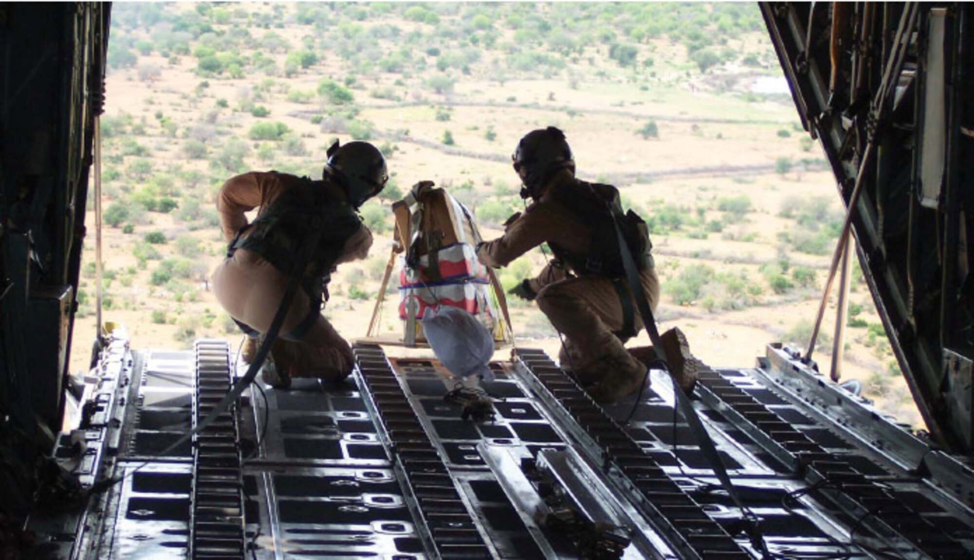 Staff Sgt. Patrick Delselva (left) and Senior Airman Chris Elder roll a miniature pallet of candy off thecargo ramp of a C-130 Hercules Dec. 14 to children in the Dadaab region of northeastern Kenya. Both Airmen are deployed to the 746th Expeditionary Airlift Wing from Dyess Air Force Base, Texas. (U.S. Air Force photo/Tech. Sgt. Stephen Staedler)