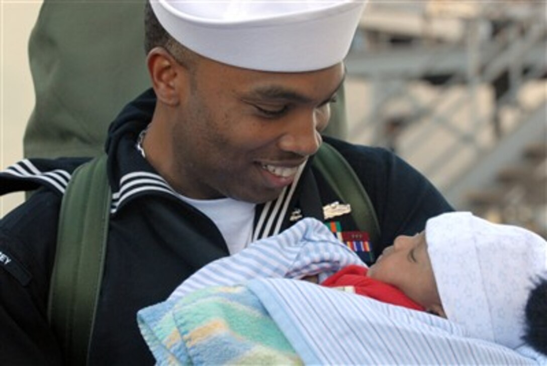 A U.S. Navy sailor holds his child for the first time as he returns to Naval Base San Diego, Calif., following a deployment aboard the USS Halsey (DDG 97) on Dec. 24, 2006.  Halsey, an Arleigh Burke class guided-missile destroyer, conducted sustained maritime interdiction operations in the Sulu and Celebes Seas during its maiden deployment.  