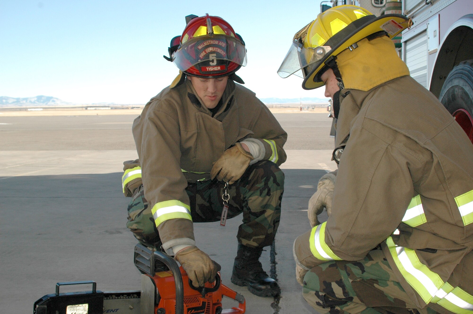 Staff Sgt. Adam Tisher, a fire fighter crew chief with the 341st Civil Engineer Squadron at Malmstrom Air Force Base, Mont., shows Airman 1st Class Christina Fowler how to use a chainsaw during training. (U.S. Air Force/Valerie Mullett)