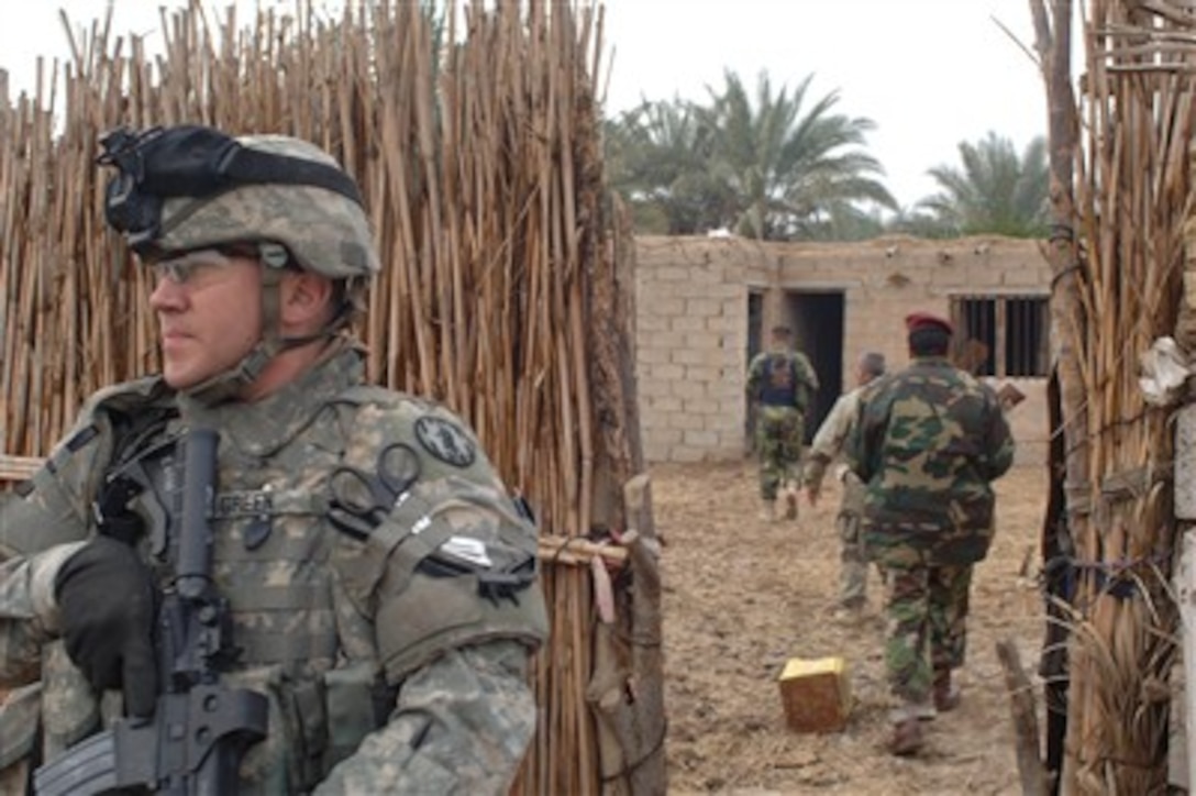 A U.S. Army soldier stands outside a fence to provide security as Salman Pak Iraqi police officers conduct a cordon and search operation for insurgents in the Al Jara area of East Baghdad, Iraq, on Dec. 22, 2006.  