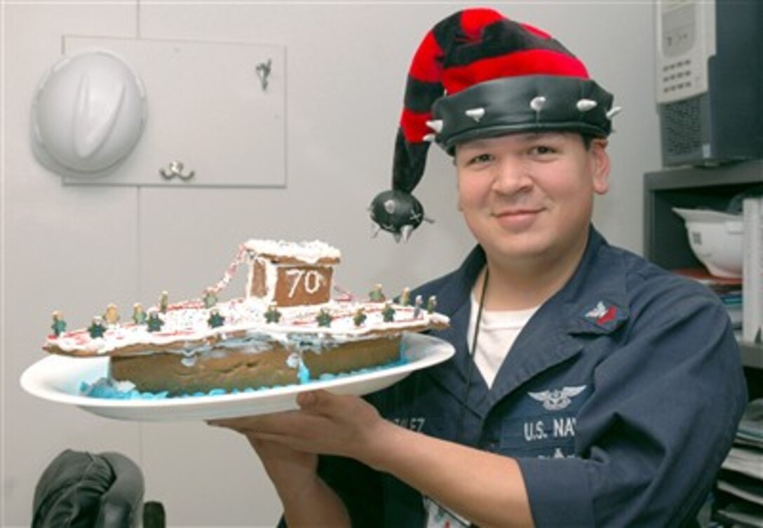 U.S. Navy Petty Officer 2nd Class Carlos Gonzalez, assigned to the USS Carl Vinson, displays his gingerbread version of the Carl Vinson prior to the ship’s holiday feast for the duty section, Dec. 25, 2006.