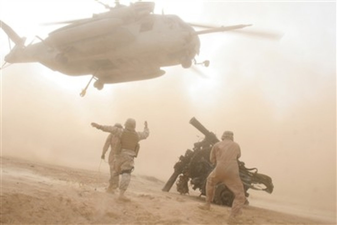 U.S. Marines direct the crew of a CH-53E Super Stallion helicopter as it prepares to pick up a rotor head from a downed CH-53E near Al Qa'im, Iraq, on Dec. 15, 2006.  Marines with Heavy Marine Helicopter Squadron 465 are deployed with I Marine Expeditionary Force in support of Operation Iraqi Freedom.  