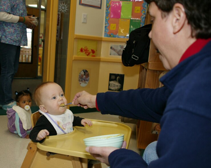 SHAW AIR FORCE BASE, S.C. -- Jacob, son of Senior Airmen Amanda and Marc Taylor, both assigned to the 20th Component Maintenance Squadron, smiles Dec. 28 between spoonfuls of food from Joni Larrimer, 20th Services Squadron child development program assistant. (U.S. Air Force photo/Tarsha Storey)