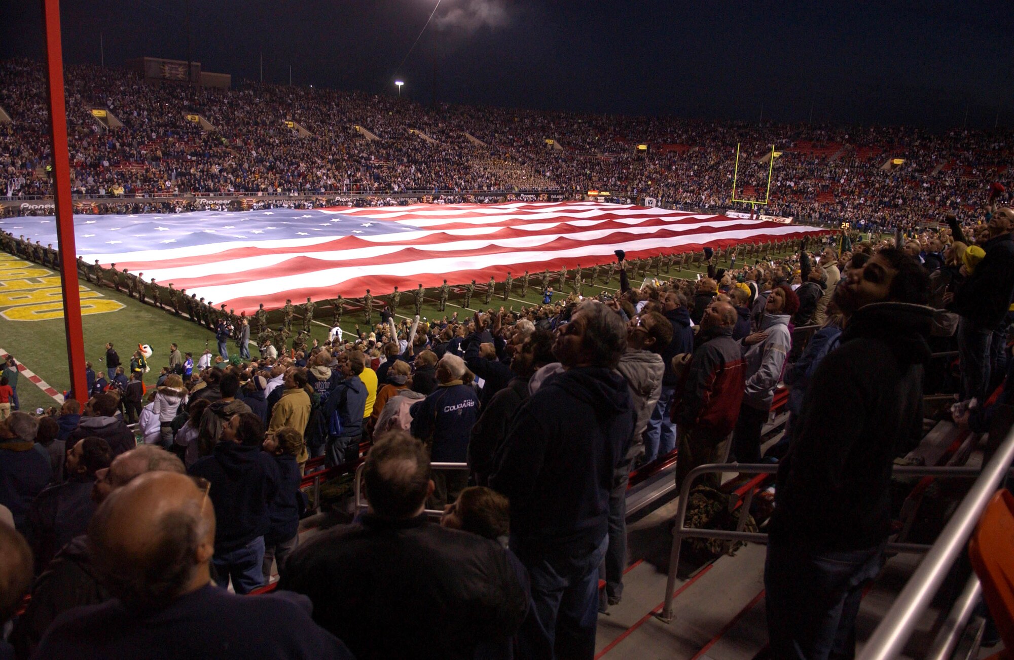 250 Airmen hold a 100-yard-by-50-yard American flag across the football field at the Las Vegas Bowl Dec. 21 while football fans look skyward as two F-15E Strike Eagles fly over the stadium during the national anthem. The Airmen and F-15s are from Nellis AFB, Nev. (U.S. Air Force photo/Tech. Sgt. Justin D. Pyle)