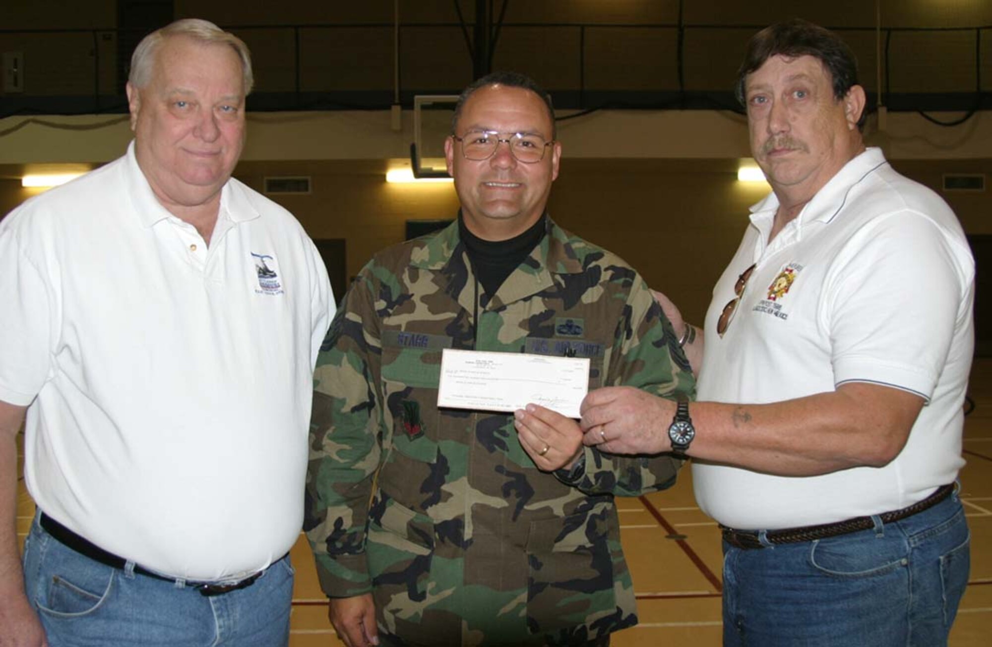 Mr. Terry Benson and Mr. Chip Bar from the Alamogordo chapter of Veterans of Foreign Wars present Master Sgt. Brian Starr, 49th Services Squadron, on behalf of his commander, Maj. Raymond Madrid, deployed as the commander of the 376 Expeditionary Services Squadron, Dec. 7. The money funded the hats to place on a POW/MIA table at the deployed location. (U.S. Air Force photo courtesy of Master Sgt. Brian Starr)