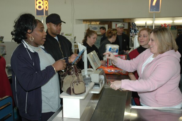 Sheilah Franklin (left) and her husband, Army Sgt. Derrick Franklin, react in surprise when told by Laurelle Dicks (right) their holiday grocery tab had just been paid courtesy of Operation Holiday Surprise sponsored by the Ramstein Enlisted Spouses Association. Cashier Sheila Medina, who was also in on the surprise, looks on. (U.S. Air Force photo/Master Sgt. Chuck Roberts)