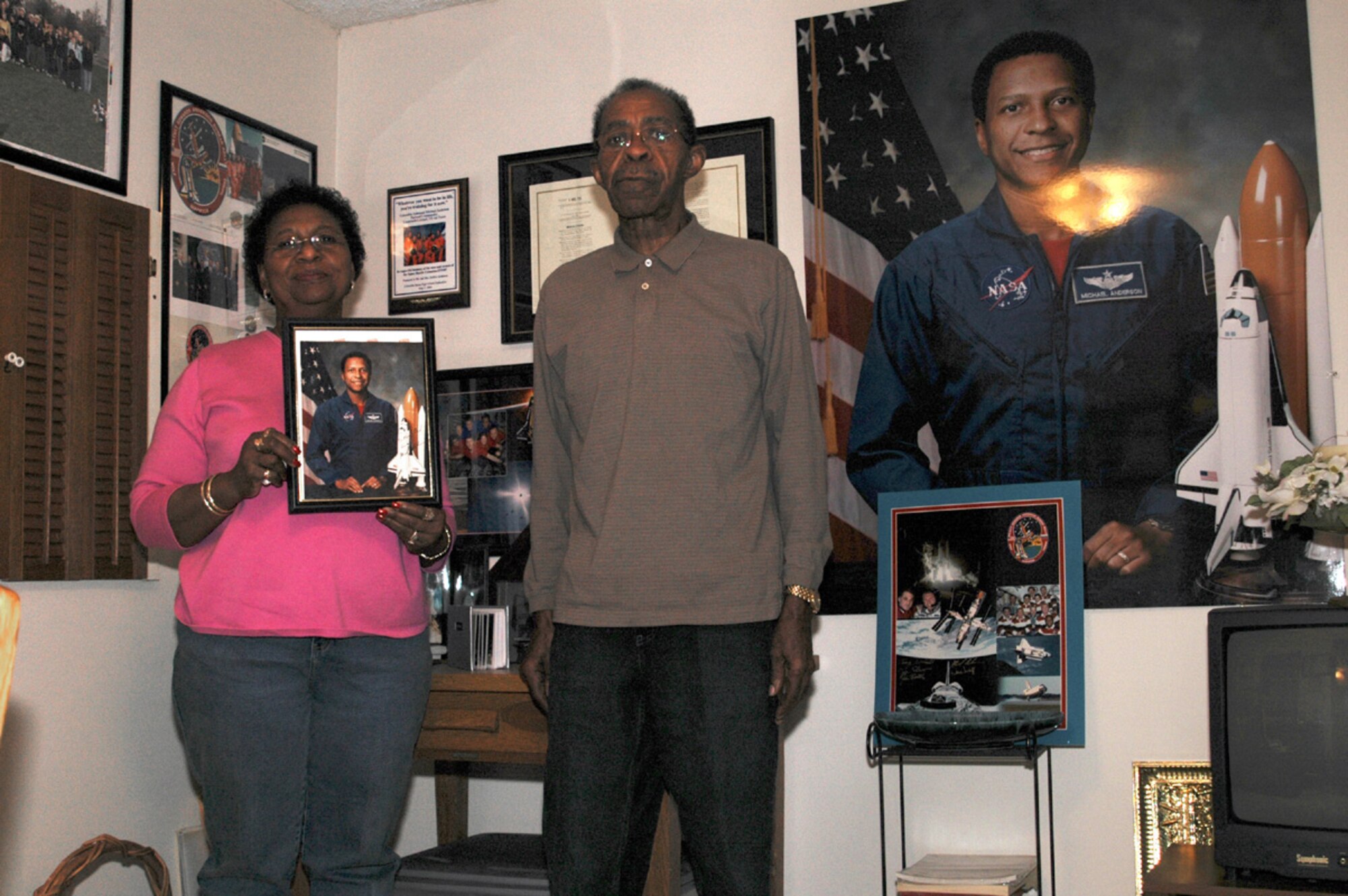 FAIRCHILD AIR FORCE BASE, Wash. (AFPN) -- Barbara and Bobby Anderson, parents of astronaut Lt. Col. Michael Anderson, hold up a picture of their son in the basement of their Spokane, Wash., home. Colonel Anderson was one of only a handful of African-American astronauts and one of seven crewmembers aboard the Space Shuttle Columbia when it exploded on re-entry just minutes before its scheduled touchdown Feb. 1, 2003. (U.S. Air Force photo by Senior Airman Christie Putz)