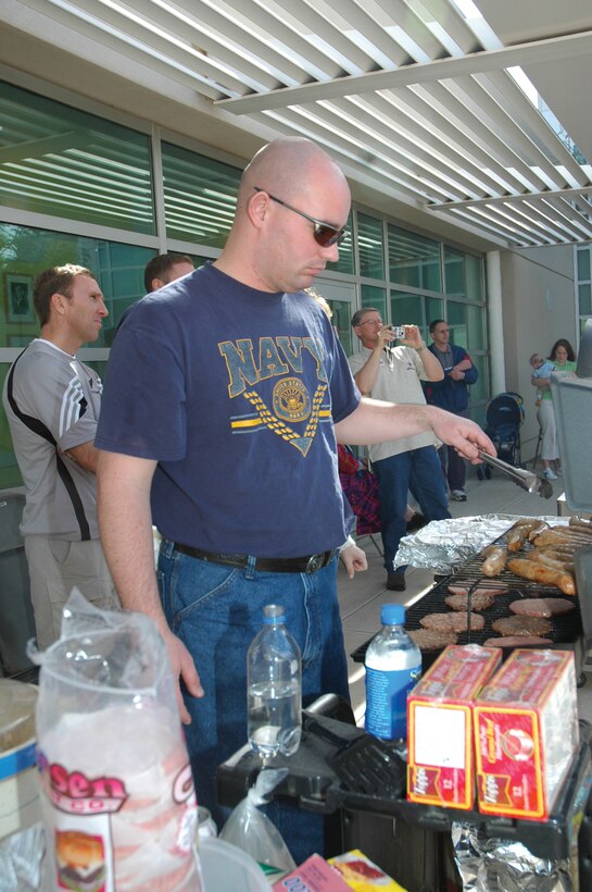 Petty Officer 2nd Class Mike Yelland, Branch Medical Clinic supply petty officer, grills up hamburgers and sausages at the BMC?s 3rd Annual SuperBowl Tailgate Party Feb. 2 here.  Super Bowl party attendees also had the opportunity to sign up for various games including ?toss the egg,? a marshmallow-eating competition, banana-eating competition and who could drink a can of soda the quickest.