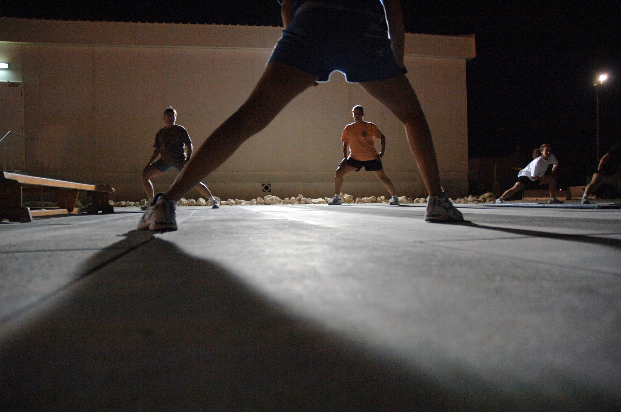 SOUTHWEST ASIA (AFPN) -- Royal Air Force Corporal Lyn McCartney leads American, English and Australian airmen in stretching exercises before the start of a "combat aerobics" class here Feb. 2. The class is offered three nights a week and helps deployed airmen stay in shape.  (U.S. Air Force photo by Staff Sgt. Joshua Strang)