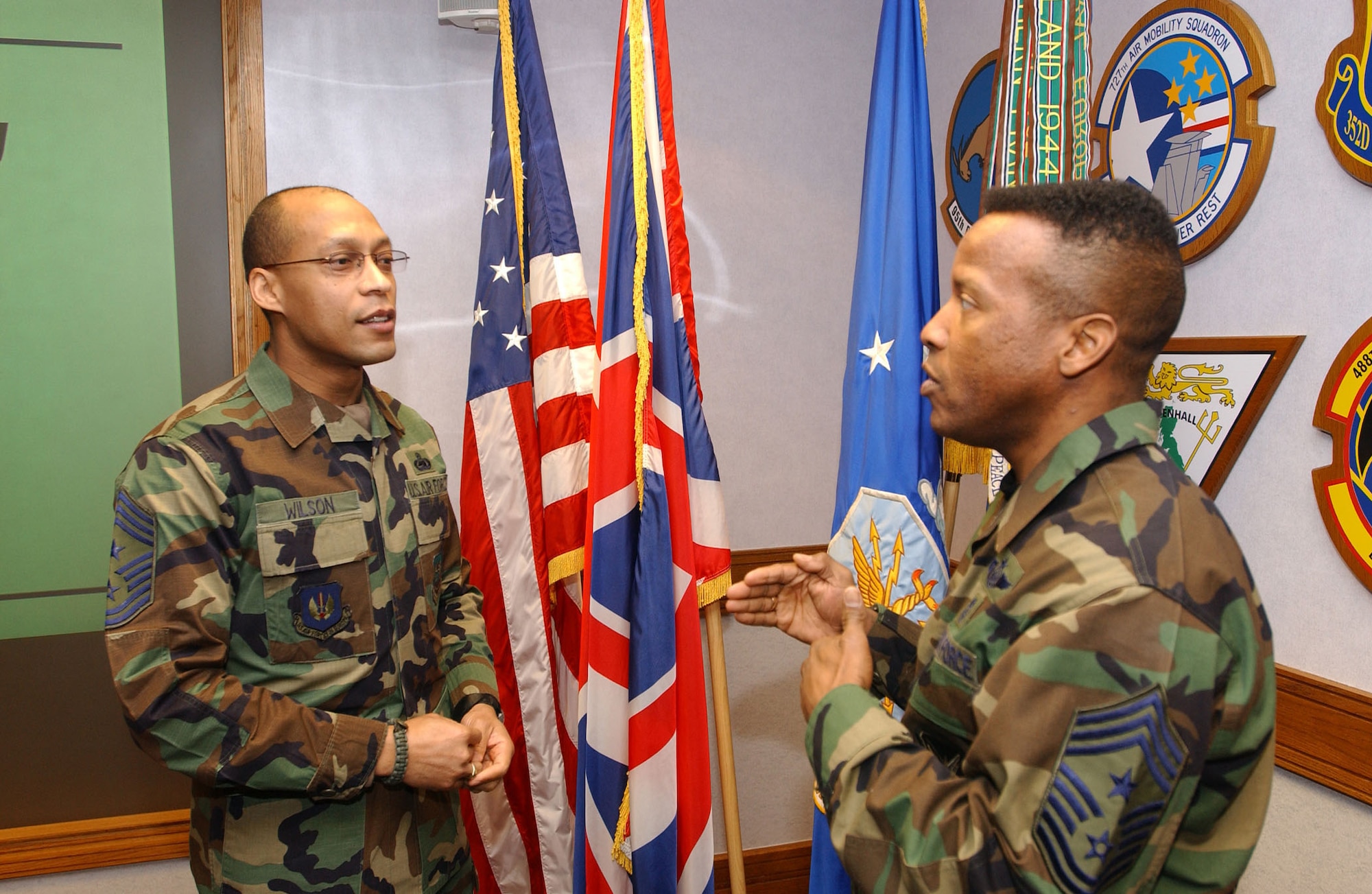 ROYAL AIR FORCE MILDENHALL, England (AFPN) -- Chief Master Sgt. Angelo Wilson talks with Chief Master Sgt. Jeffrey Richardson before the wing stand-up meeting Feb. 1. Chiefs Wilson and Richardson came from different backgrounds, but both saw the opportunities the Air Force provided. Chief Wilson is the command chief master sergeant for the 100th Air Refueling Wing. Chief Richardson is the command chief master sergeant for the 352nd Special Operations Group. (U.S. Air Force photo) 
