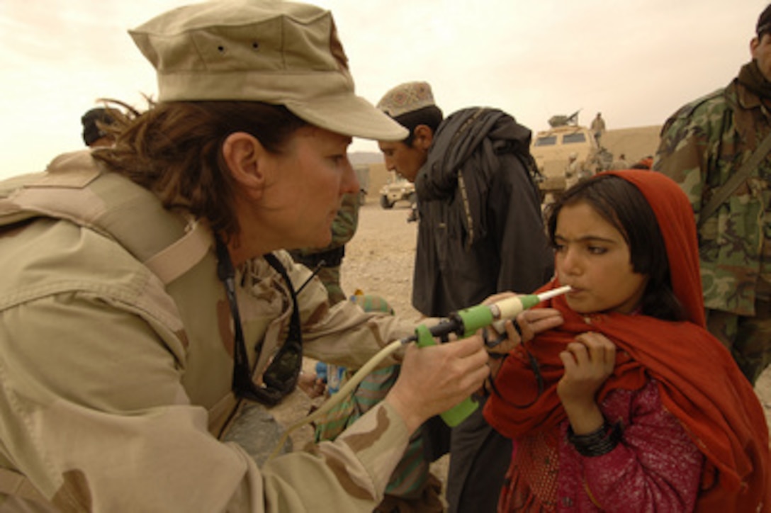 U.S. Navy Lt. Cmdr. Kim Kaufman gives a dose of de-wormer medication to an Afghan girl during a village medical outreach in Maywand District, Afghanistan, on Jan. 27, 2006. 