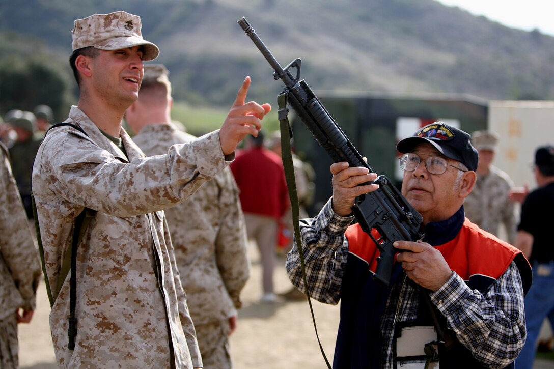 Pvt. Paul J. Perico, 21, of North Port, N.Y., and an assault man with Weapons Company 1st Battalion, 5th Marine Regiment, shows 78-year-old Korean War veteran Rick H. Salinas of San Jose how to properly handle an M-16 A4 during a live fire event at Camp Day Feb. 2. More than 100 members of the 1st Marine Division Association assembled aboard Camp Pendleton for 1st Marine Division's 65th anniversary. Celebrations for the "Blue Diamond's" 65th included live fire exercises, displays of the Marine Corps Martial Arts Program and other events, which were held aboard the base Jan. 31 - Feb. 2.