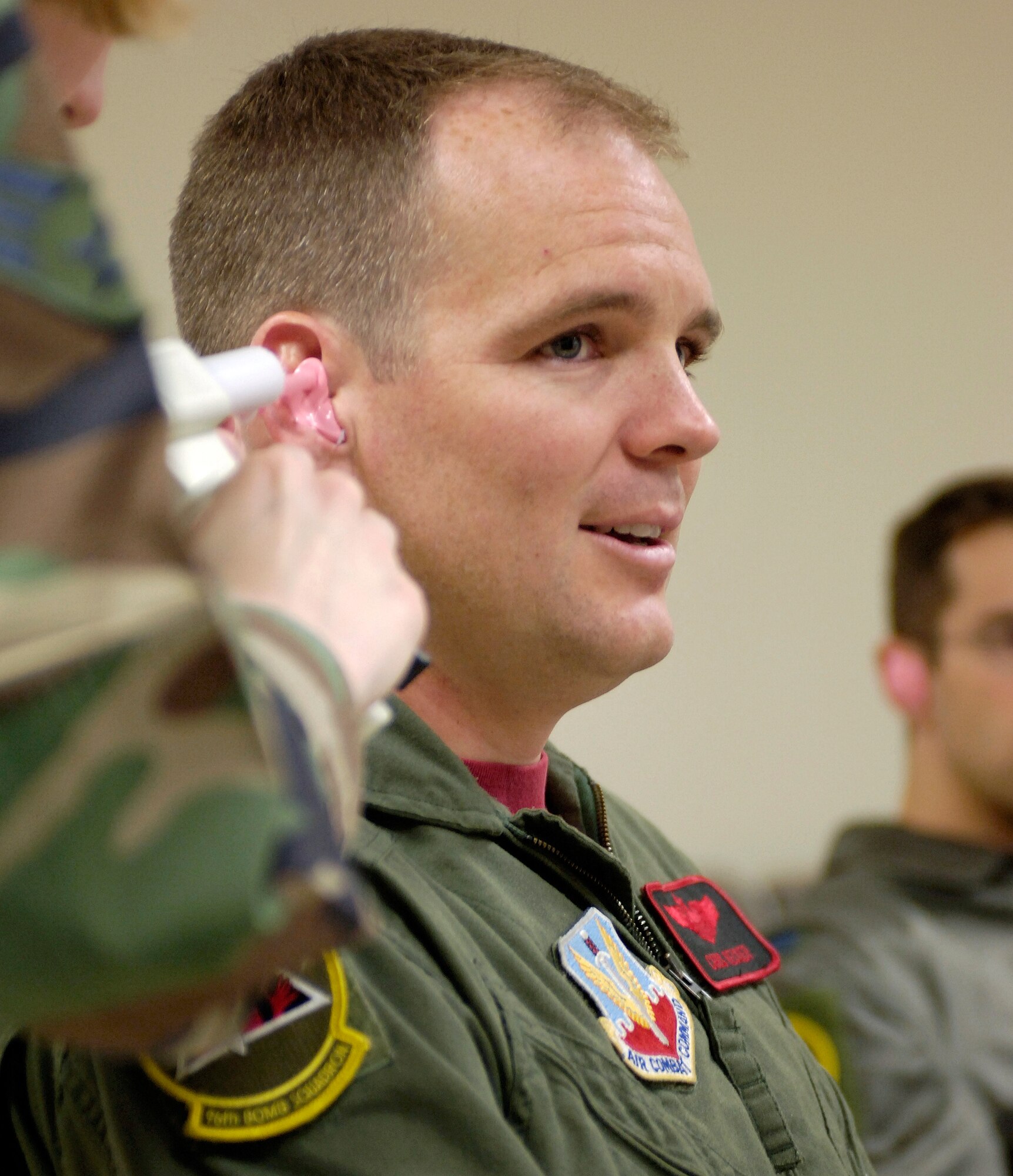 BARKSDALE AIR FORCE BASE, La. (AFPN) -- Senior Airman Angela Stapperich uses a silicone material to mold the ear of Maj. Chris Recker.  The mold will be used to create the Air Force's newly approved attenuating custom communications earpiece system, or ACCES.  Each earpiece is custom-fit to the individual's ear canal and contains a built-in speaker that connects to an aircraft's communication system.  The earpieces are designed to help enhance radio fidelity, reduce ambient noise, increase situational awareness and protect against potential hearing loss. Airman Stapperich is with the Air Force Research Laboratory at Wright-Patterson Air Force Base, Ohio. Major Recker is assigned to the 96th Bomb Squadron. (U.S. Air Force photo by Senior Airman Brian Ferguson)