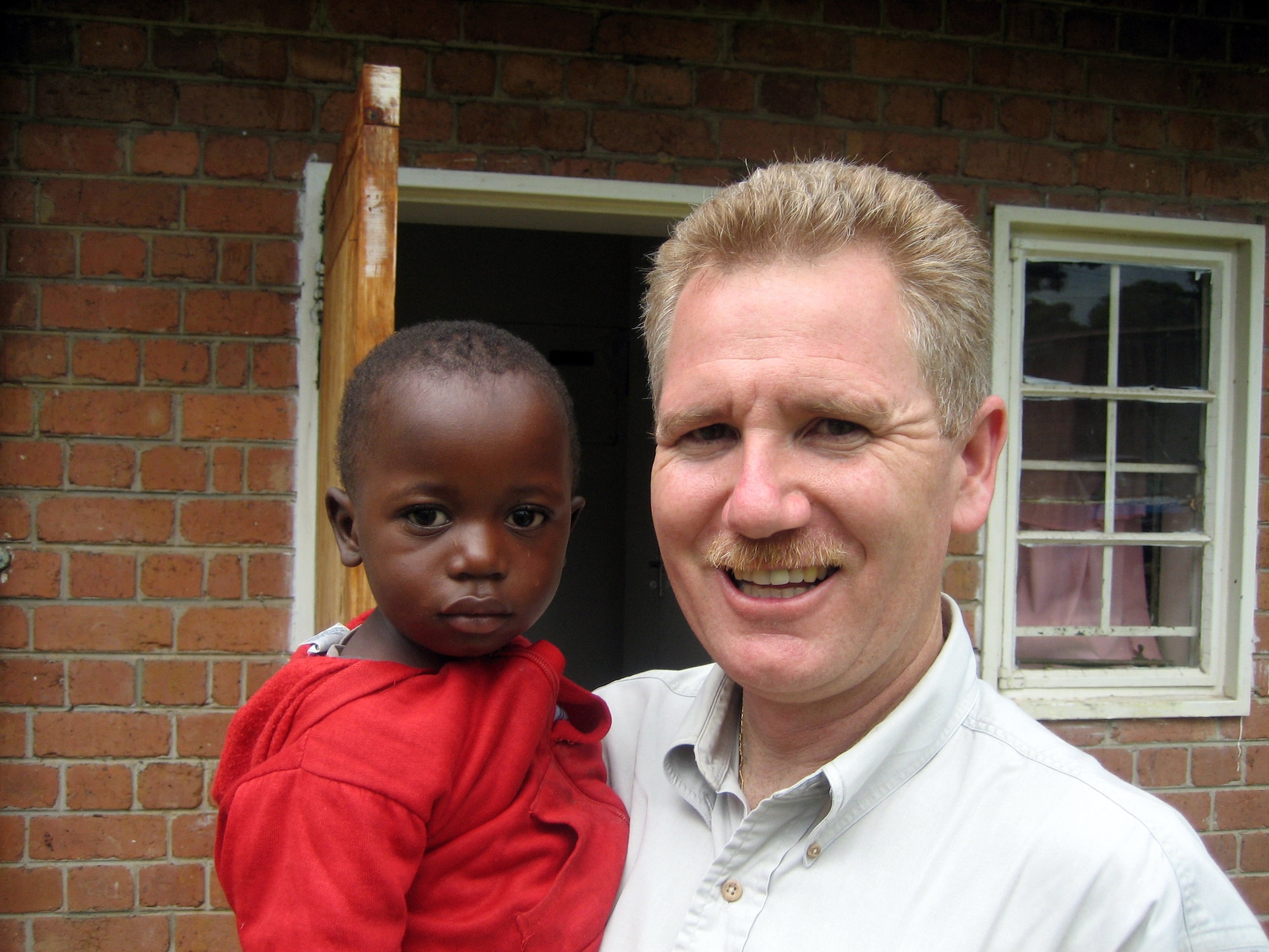 ZAMBIA (AFPN) -- Lt. Col. (Dr.) Kirk Milhoan plays with Joseph, a 9-year-old HIV-positive child, in the first AIDS orphanage built in Zambia. (U.S. Air Force photo by Kim Milhoan) 

