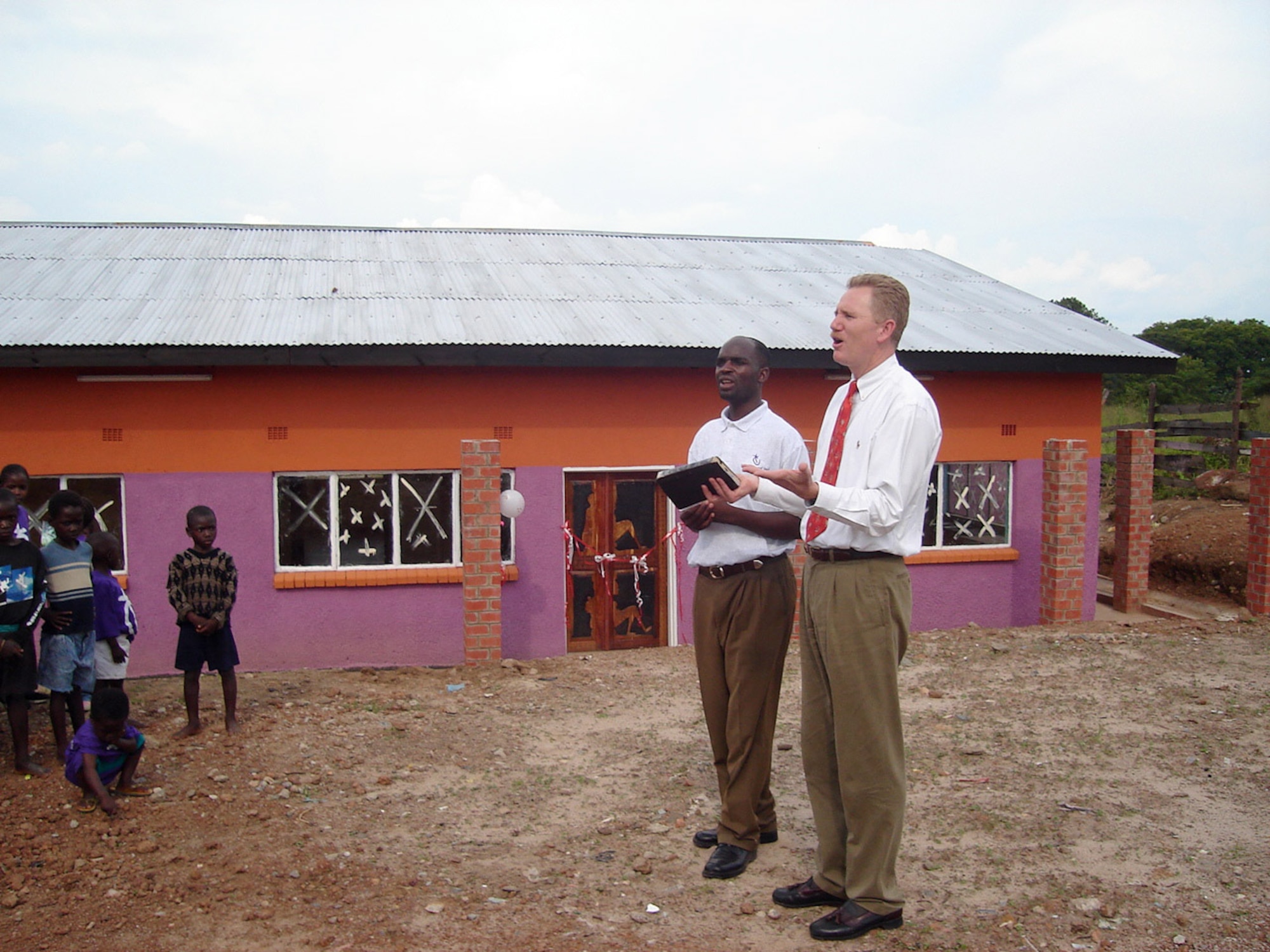 ZAMBIA (AFPN) -- Lt. Col. (Dr.) Kirk Milhoan (right) joins Edward Mwansa, pastor and onsite orphanage director, in leading a dedication ceremony of the new AIDS orphanage Jan. 29. It took 14 months to build the facility. (U.S. Air Force photo by Kim Milhoan) 
