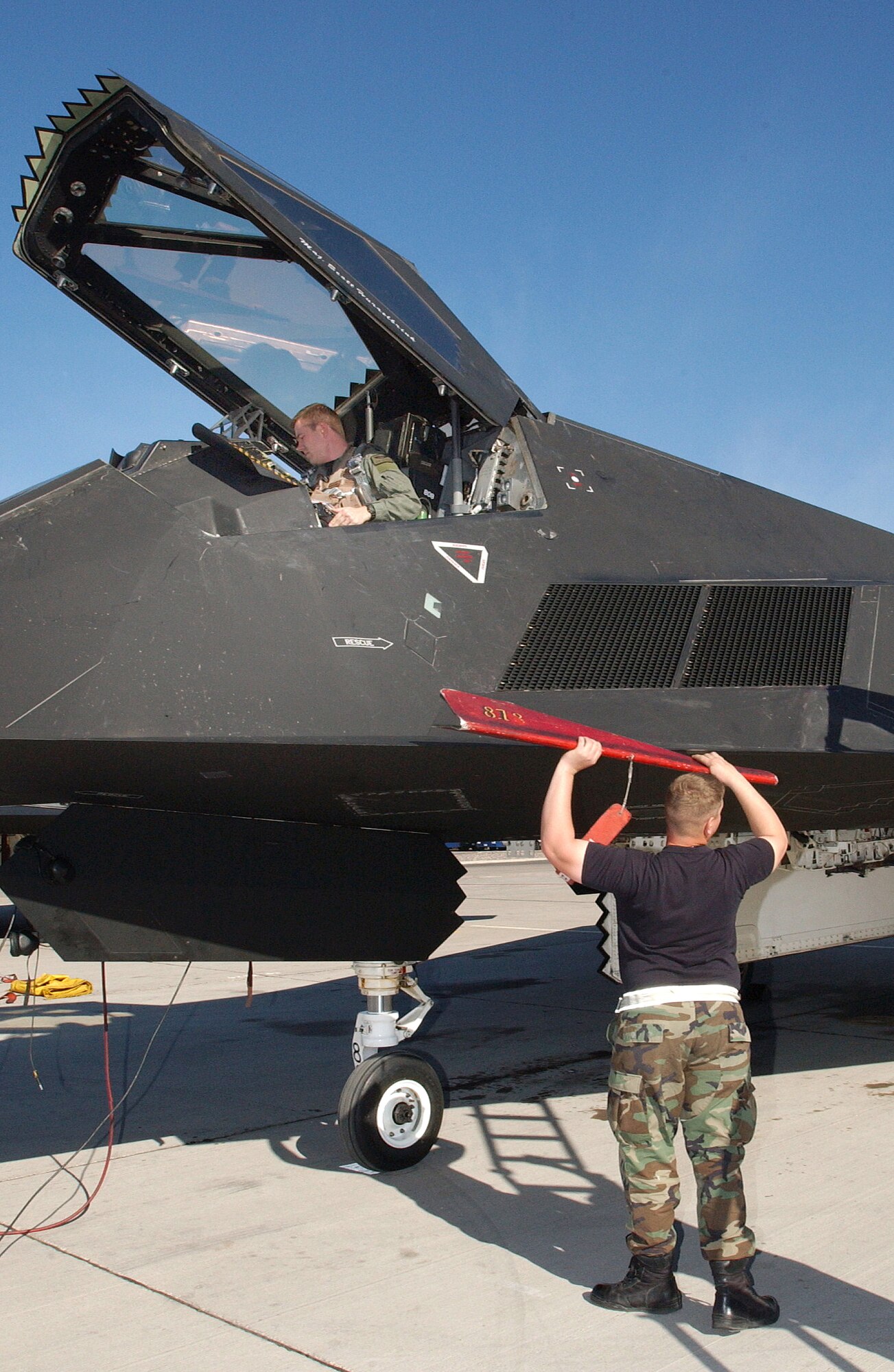 NELLIS AIR FORCE BASE, Nev. (AFPN) -- Airman 1st Class Keith Hartman removes the ladder guard after Capt. Erik Jacobson climbs into the cockpit during Red Flag 06-1, here Jan. 21 to Feb. 18.  Red Flag is an exercise that tests aircrews' warfighting skills. Flights involve more than 100 aircraft, including B-52 Stratofortresses and F-16 Fighting Falcons. The aircraft are flying missions day and night to the nearby Nevada Test and Training Range where they simulate an air war. Along with the Air Force, units from the Army, Navy, NATO and several allied countries are participating. Captain Jacobson is an F-117A Nighthawk pilot with the 49th Fighter Squadron at Holloman Air Force Base, N.M. Airman Hartman is an electrical engineering specialist with the 49th Aircraft Maintenance Squadron. (U.S. Air Force photo by Staff Sgt. Kenny Kennemer)