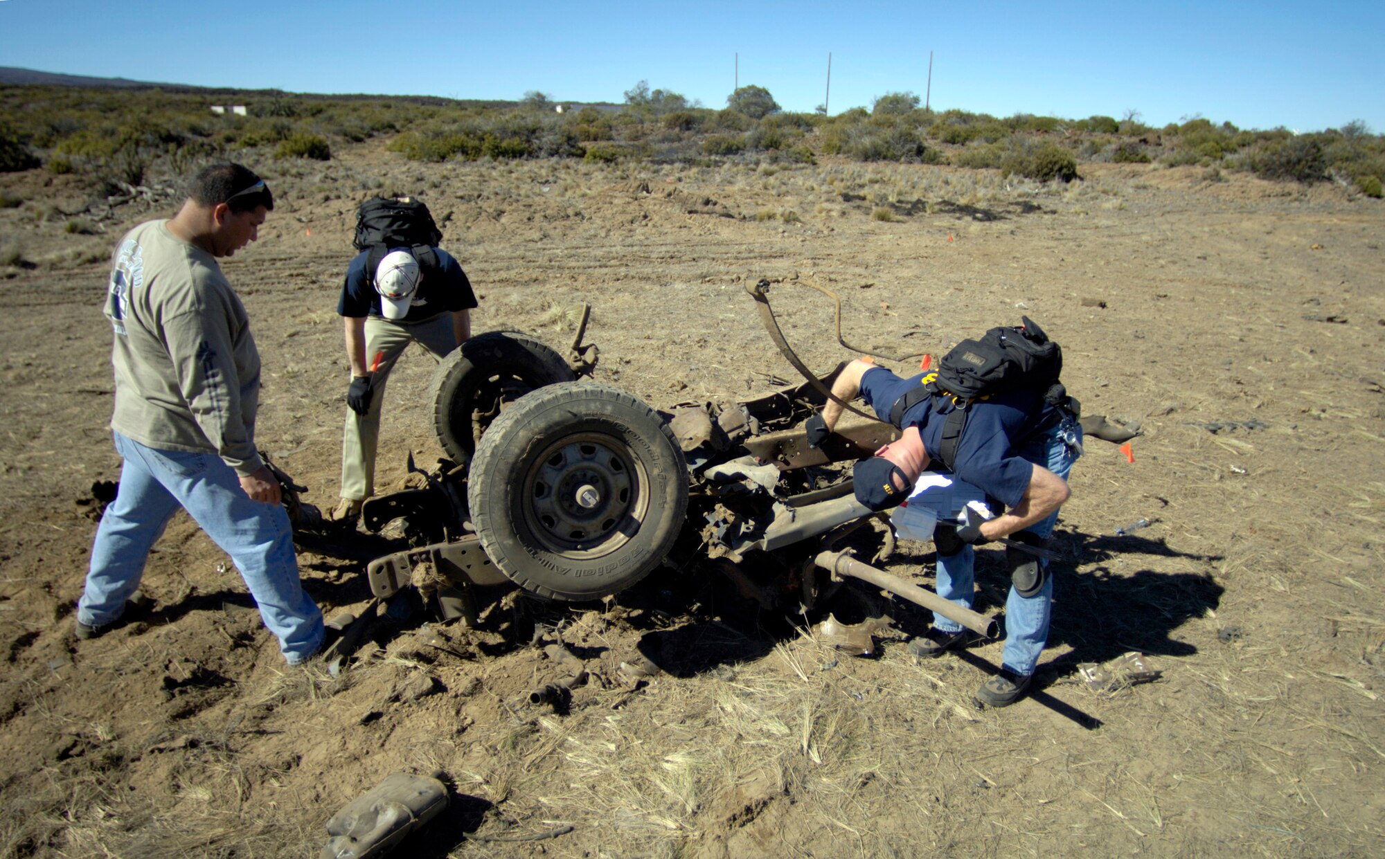 POHAKULOA TRAINING AREA, Hawaii (AFPN) -- Students search for evidence on the blown-up frame of a vehicle at a bomb scene scenario. The FBI, along with Army cadre, conducted a large vehicle post blast investigator's course here. It included instruction on investigative techniques and evidence collection. (U.S. Air Force photo by Tech. Sgt. Shane A. Cuomo)