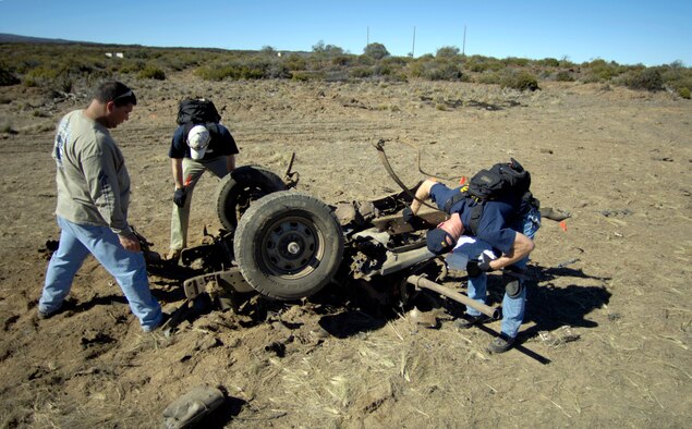 POHAKULOA TRAINING AREA, Hawaii (AFPN) -- Students search for evidence on the blown-up frame of a vehicle at a bomb scene scenario. The FBI, along with Army cadre, conducted a large vehicle post blast investigator's course here. It included instruction on investigative techniques and evidence collection. (U.S. Air Force photo by Tech. Sgt. Shane A. Cuomo)
