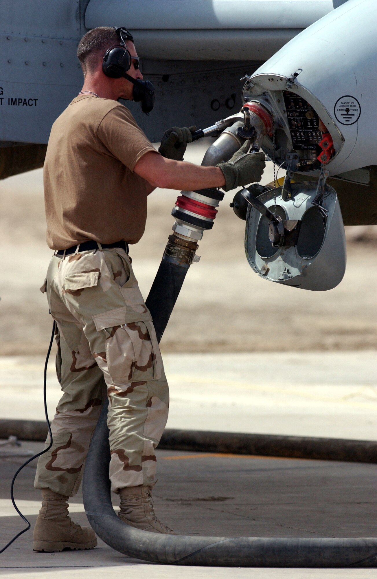 OPERATION IRAQI FREEDOM -- Master Sgt. Kevin Bossaller keeps in voice contact with the pilot as he refuels an A-10 Thunderbolt II. This was the first A-10 "hot" refuel in Iraq and the first time the R-14 fuel hydrant system was used in the hot-refuel process.  Bossaller is an A-10 crew chief with the 442nd Fighter Wing from Whiteman Air Force Base, Mo., which was deployed to Tallil and Kirkuk Air Bases in Iraq in 2003.  Air Force Reservists who were on this deployment were recently awarded the Air Force Outstanding Unit Award with a Valor Device.  (U.S. Air Force photo by Master Sgt. Terry L. Blevins)
