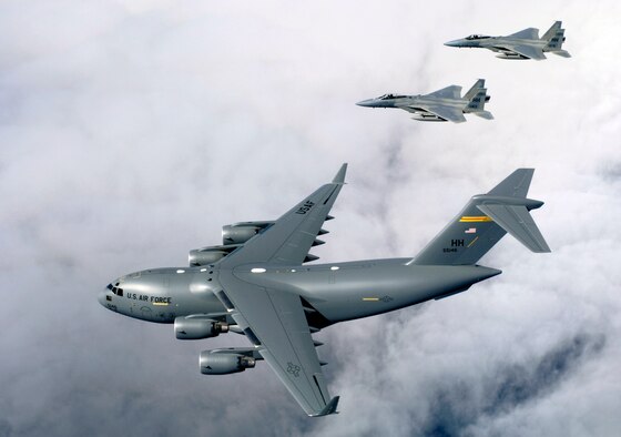 HICKAM AIR FORCE BASE, Hawaii (AFPN) -- F-15B Eagles from the 199th Fighter Squadron, 154th Wing, Hawaii Air National Guard escort the first Hawaii-based C-17 Globemaster III to its home. Hickam is the first base outside the continental U.S. to permanently host the C-17. By the end of the year the base will be home to eight C-17s. The 15th Airlift Wing and the 154th Wing will jointly operate and maintain the aircraft. (U.S. Air Force photo by Tech. Sgt. Shane A. Cuomo) 
