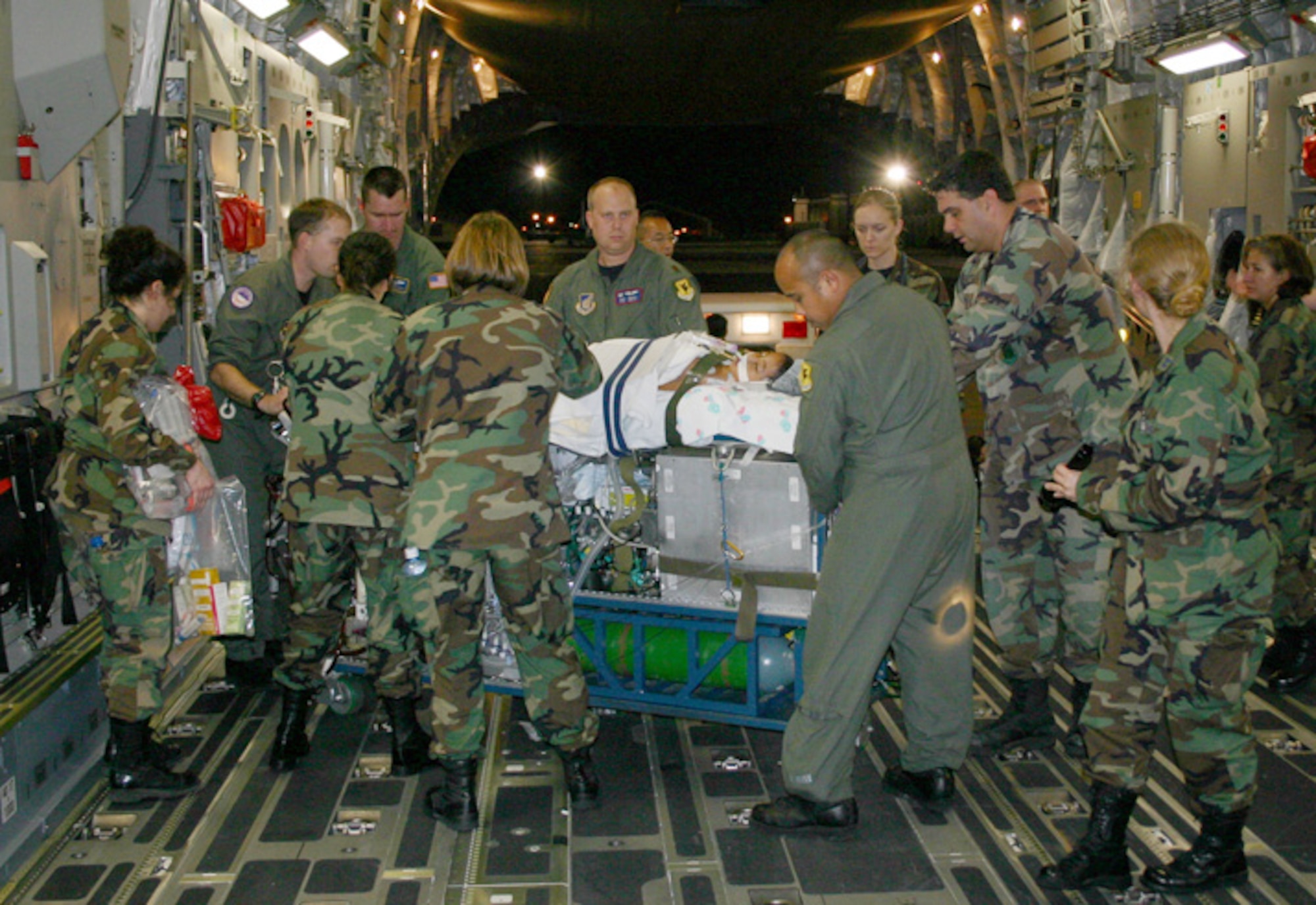LOS ANGELES (AFPN) -- The Wilford Hall medical team and C-17 Globemaster III aircrew carefully move the more than 800-pound mobile extracorporeal membrane oxygenation, or ECMO, machine and Meaghan Ababa down the aircraft ramp to a waiting ambulance for transport to the Children's Hospital in Los Angeles Feb. 4. The ECMO machine works as a heart-lung bypass machine providing temporary heart and lung function during periods of severe cardiopulmonary failure. The patient made the six-hour flight from Hawaii to Los Angeles without incident. (U.S. Air Force photo by Master Sgt. Kimberly Spencer) 
