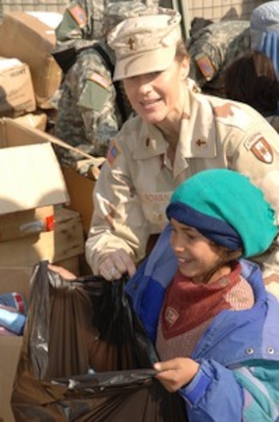 U.S. Army Chaplain Maj. Julie Rowan guides a young Afghan girl through a line to receive humanitarian supplies at the Egyptian Hospital at Bagram Airfield, Afghanistan, on Feb. 7, 2006. Rowan is attached to Task Force Strength, Combined Joint Task Force 76. Members of the task force and the Egyptian army are passing out donated items to the local villagers. 