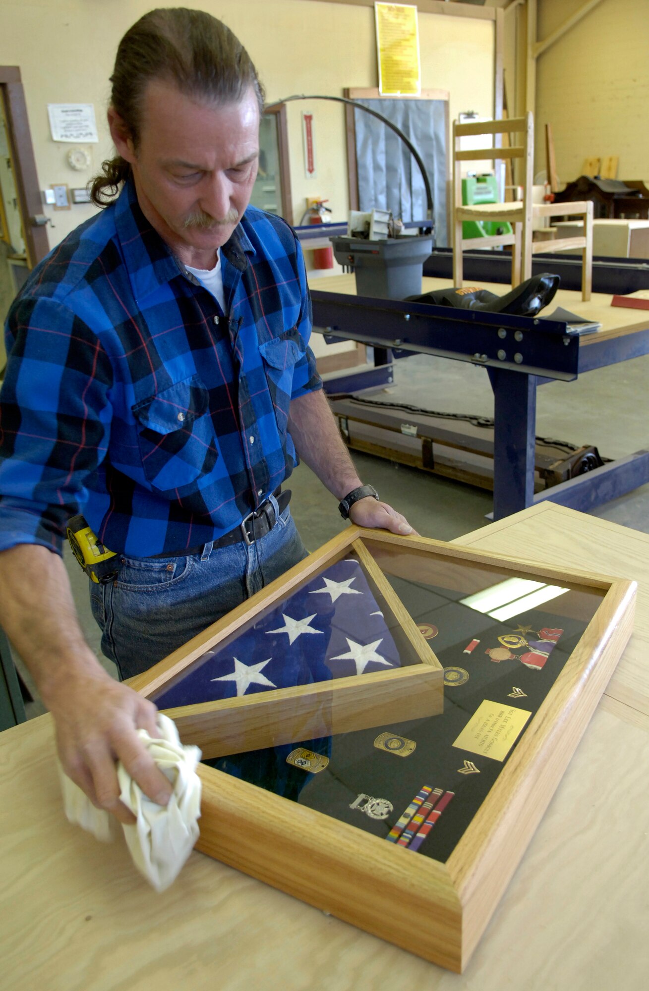 BARKSDALE AIR FORCE BASE, La. (AFPN) -- Retired Tech. Sgt. Mike Jarrett, woodcraft manager here, cleans up the shadow box he plans to present to the mother of Army Sgt. Lee Myles Godbolt. Mrs. Godbolt, a Hurricane Katrina evacuee, lost most of her belongings in the storm, but was able to save the damaged shadow box of her son who was killed in Iraq. Sergeant Jarrett and his wife heard this story on the local news. They both decided they would replace Sgt. Godbolt's shadow box for his mother. (U.S. Air Force photo by Senior Airman Brian Ferguson) 
