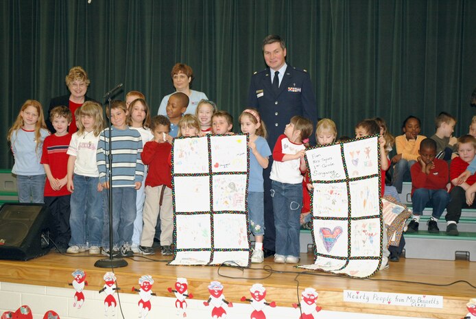 First-grade children at Sangree Elementary School in Summerville, S.C. present "Quilts of Valor" to Chaplain (Maj.) John Painter (center), a reservist assigned to the 315th Airlift Wing at Charleston AFB, S.C.  Chaplain Painter accepted two quilts on behalf of his civilian employer the Ralph H. Johnson VA Medical Center and two quilts that will be delivered by the 315th Airlift Wing to a regional hospital in Germany. (Photo by Tech. Sgt. Mark Kleber, USAFR)