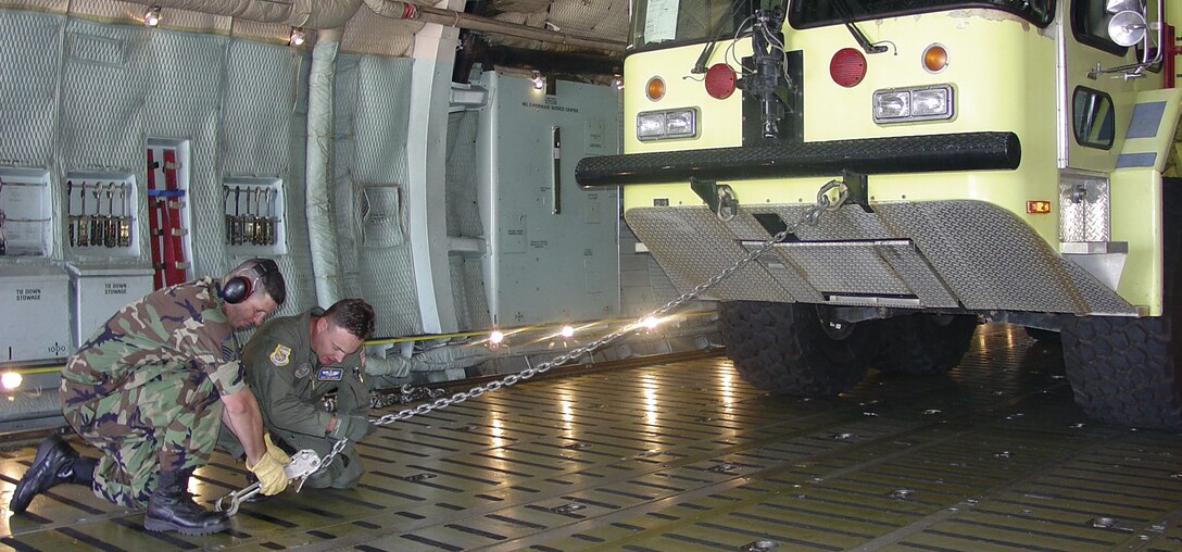 Master Sgt. David Champagne, 41st Aerial Port Squadron and Master Sgt. Wes Askew, 97th Air Mobility Wing, chain down a fire truck in a C-5 at Gulfport National Guard Base, Miss. for return to Goodfellow Air Force Base, San Angelo, Texas. The firetruck was airlifted to to Biloxi as part of the Air Force's post-Hurricane Katrina response. 