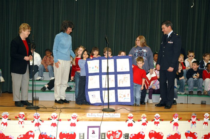 First-grade children at Sangree Elementary School in Summerville, S.C. present "Quilts of Valor" to Chaplain (Maj.) John Painter (right), a reservist assigned to the 315th Airlift Wing at Charleston AFB, S.C.  Chaplain Painter accepted two quilts on behalf of his civilian employer the Ralph H. Johnson VA Medical Center and two quilts that will be delivered by the 315th Airlift Wing to a regional hospital in Germany. (Photo by Tech. Sgt. Mark Kleber, USAFR)