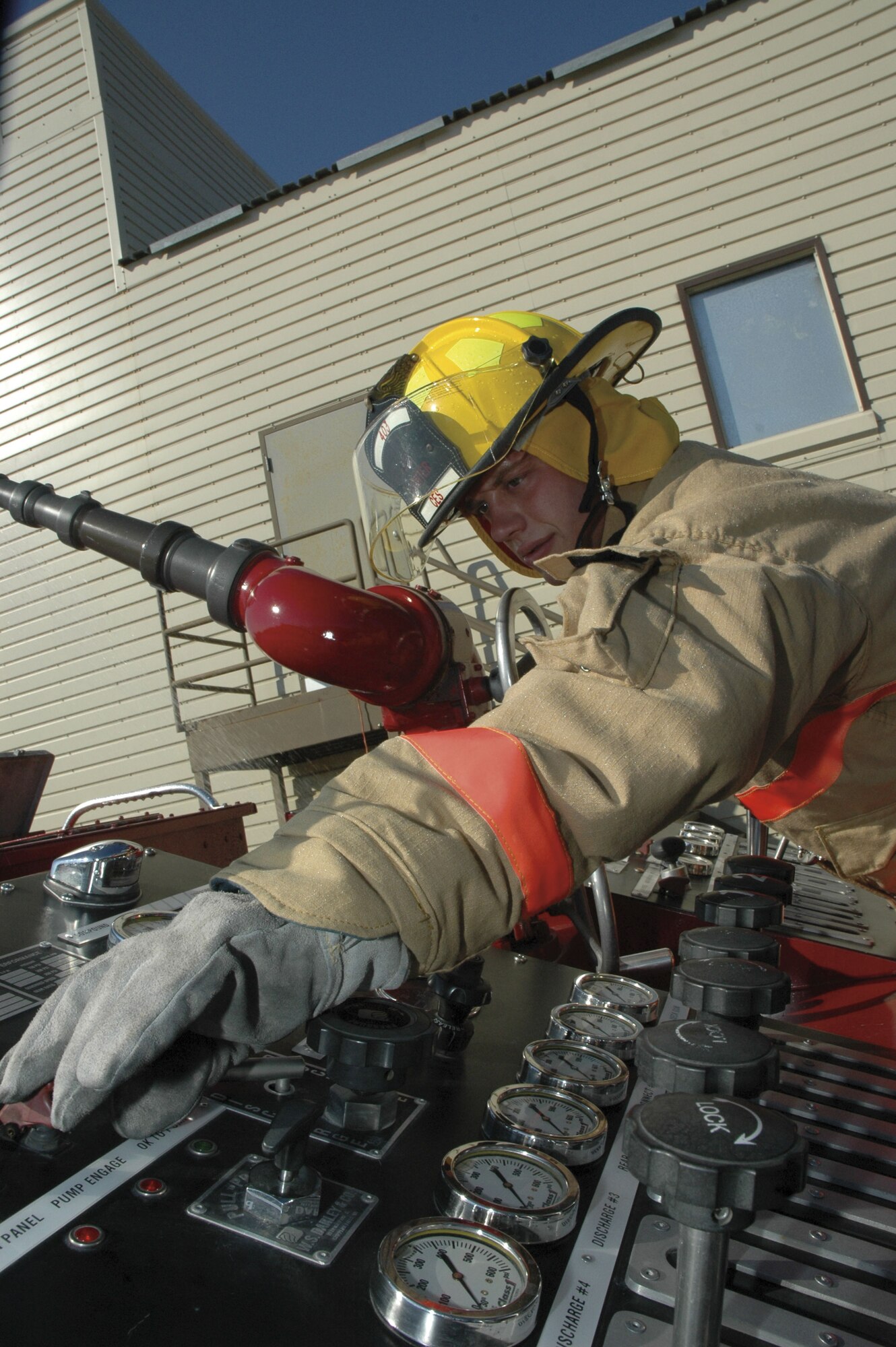 Airman 1st Class Jonathan Padgett, a firefighter with the 403rd CES Fire Department, goes through pump operations on the pump panel on a fire truck. While Airman Padgett works the pump panel, a pair of his fellow firefighters are clearing the smoke from a building during training.