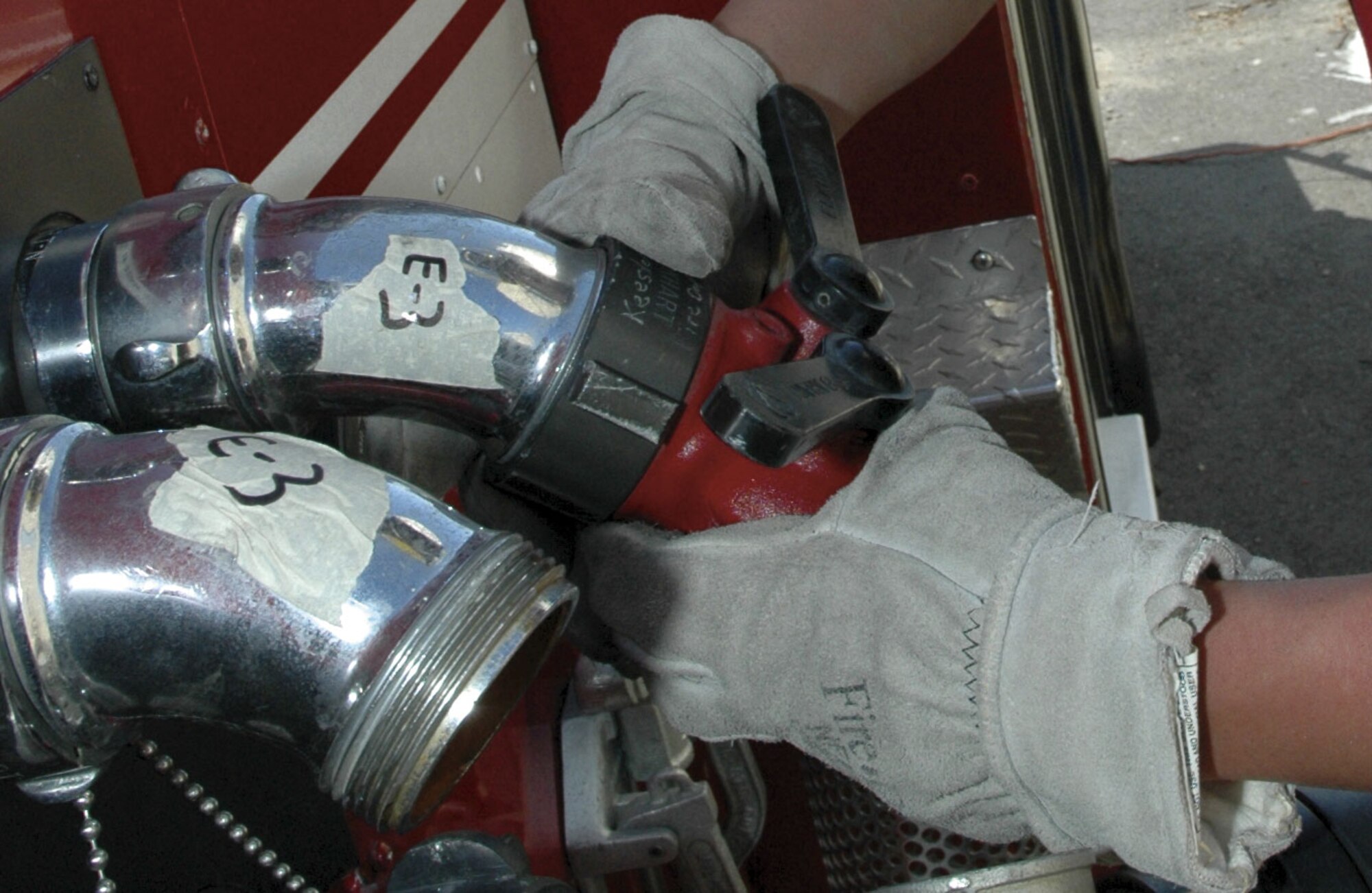 A firefighter with the 403rd CES Fire Department, attaches a hose to the discharge outlet of a fire truck.