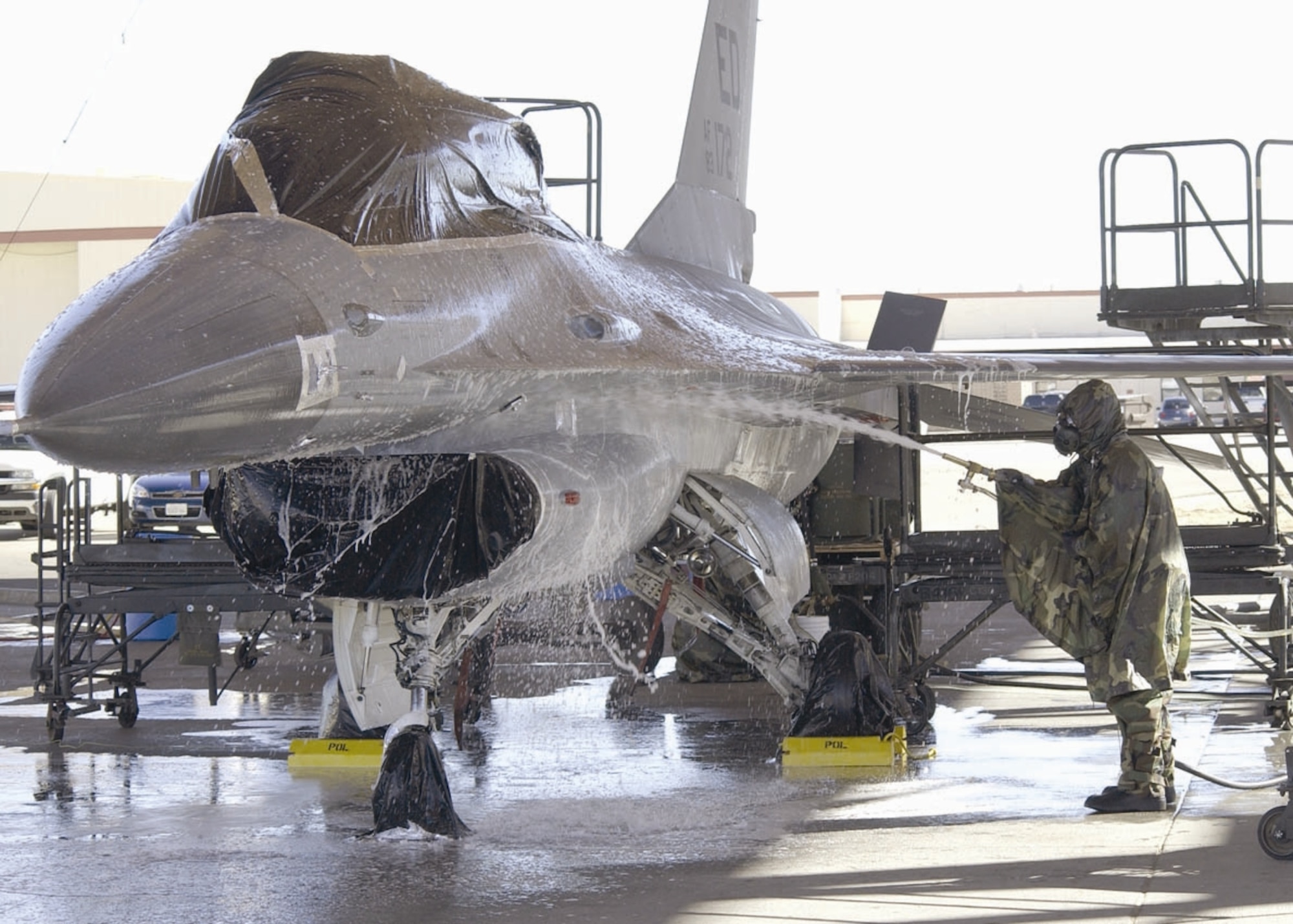 EDWARDS AIR FORCE BASE, Calif. (AFMCNS) — Members of the Joint Strike Fighter Integrated Test Force here prepare an F-16 for a final chemical decontamination test here Jan. 30. The F-16, used in place of an F-35, was sprayed with a chemical simulant, washed, then towed into a hangar and heated from 165- to 185-degree temperatures to accelerate the weathering of the remaining chemical. The goal of the testing is to decontaminate an entire aircraft to quickly return it to service should it be exposed to a chemical or biological agent. (Air Force photo by Mark McCoy)

