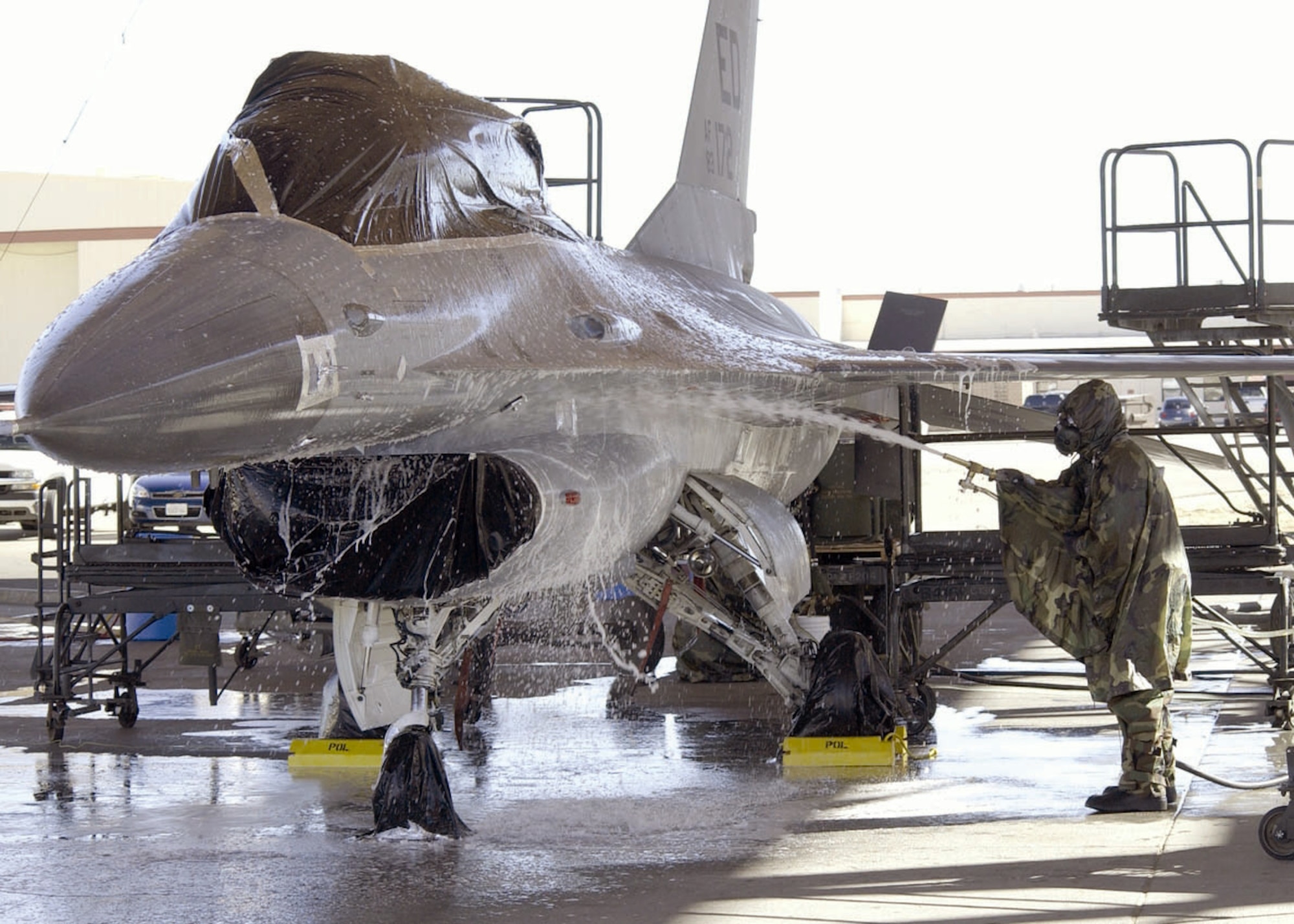EDWARDS AIR FORCE BASE, Calif. (AFPN) -- An Airman with the Joint Strike Fighter Integrated Test Force sprays down an F-16 Fighting Falcon before its final chemical decontamination test Jan. 30. The goal of the testing is to decontaminate an entire aircraft quickly and return it to service. (U.S. Air Force photo by Mark McCoy)
