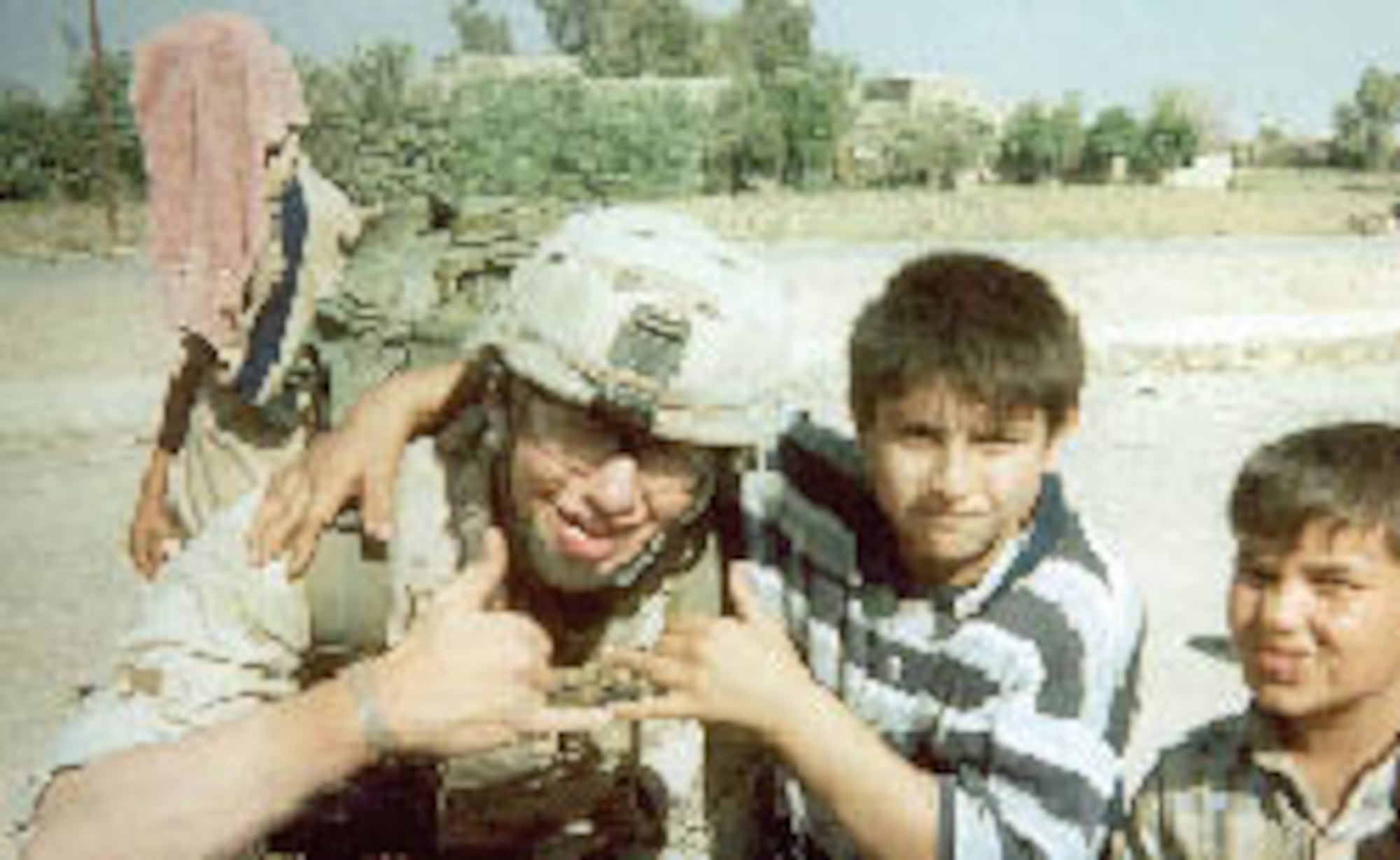 MCCHORD AIR FORCE BASE, Wash. - Army Specialist Mitch Barone, the combat medic who came to the aid of Army Sgt. Jeff Beltran, poses with children in Iraq. After receiving medical care from one Barone, Sergeant Beltran was then cared for on an aeromedical evacuation flight by Tech. Sgt. Selina Barone. Sergeant Barone is a Reservist with the 446th Airlift Wing here and Specialist Barone's mother.