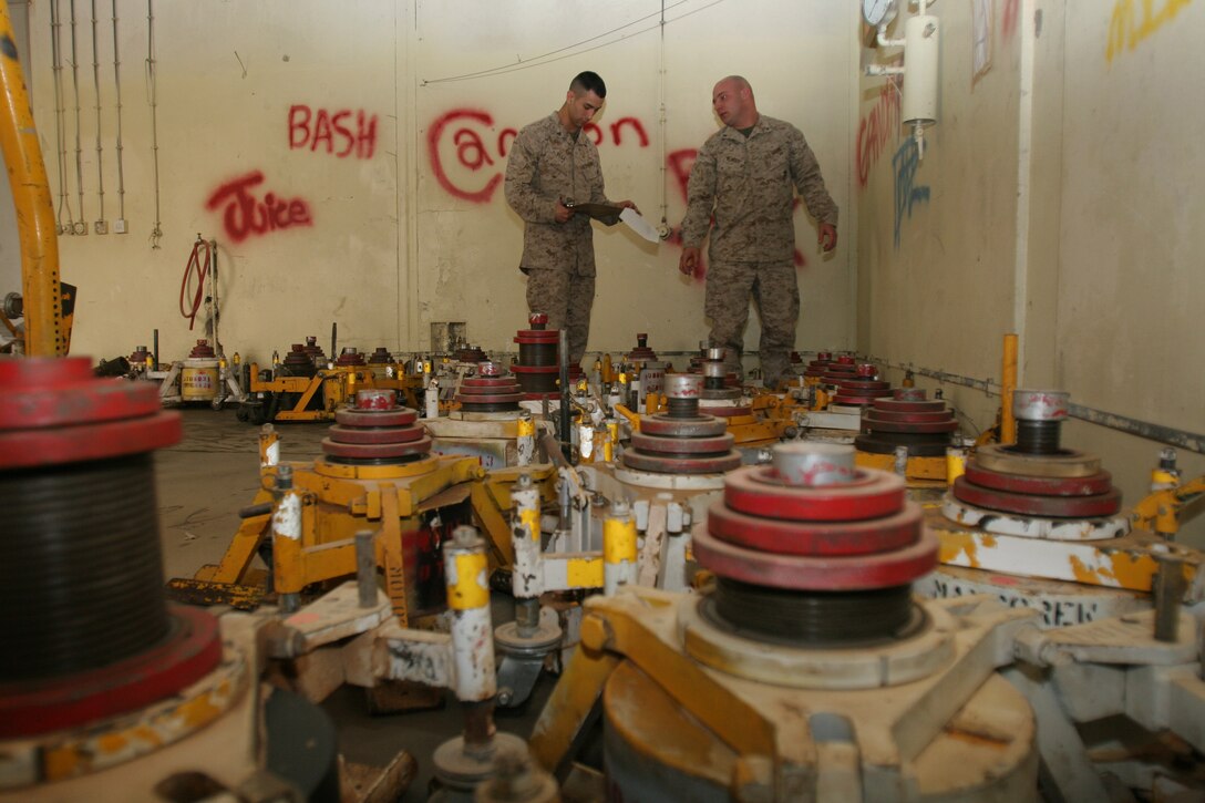 Amidst a sea of aircraft jacks, Lance Cpl. Steven G. Klinger (right) reads off serial numbers to Cpl. Stephen G. Vega during an inventory of the equipment, Feb. 13. The Marines are with the Individual Material Readiness List section which is responsible for tracking inventory for more than 3,000 pieces of aviation equipment located on Forward Operating Bases throughout Iraq. The section is part of Marine Aviation Logistics Squadron 16, Marine Aircraft Group 16 (Reinforced), 3rd Marine Aircraft Wing, and supports Marine aviation squadrons operating in the country. Klinger is an IMRL manager and Berwick, Penn., native. Vega is also an IRML manager and Orlando, Fla., native.