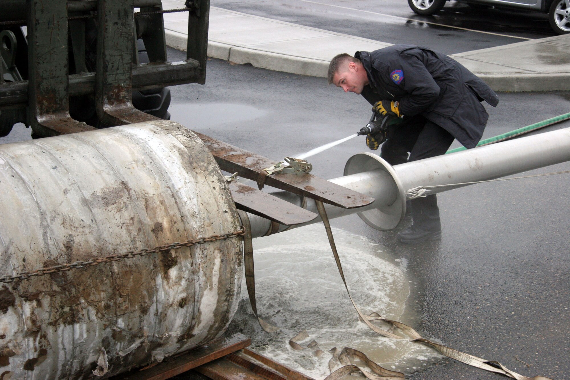 PORTLAND, Ore. (AFPN) -- Craig Thomas sprays the sand from the base of a flag pole that was removed from in front of the 939th Air Refueling Wing building here. Mr. Thomas is a firefighter with the 142nd Civil Engineer Squadron. (U.S. Air Force photo by Ruby Zarzyczny)

