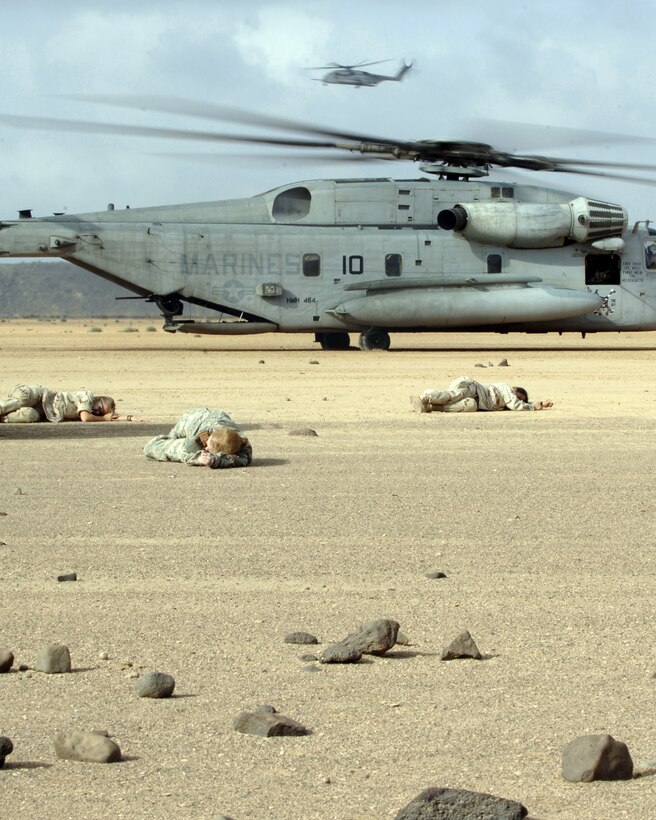CAMP LEMONIER, DJIBOUTI, Africa (AFPN) -- U.S. military members lay on the ground simulating a car crash injury, while Air Force pararescuemen in a Marine CH-53 Super Stallion helicopter prepare to pick them. The scenario was part of a search and rescue exercise here Feb 8. (U.S. Air Force photo by Staff Sgt. Ricky A. Bloom)
